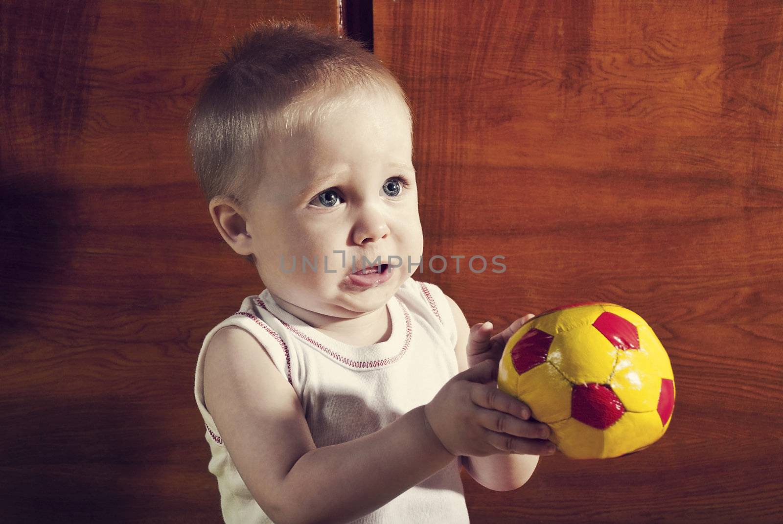 Funny boy with a soccer ball in his hands on an abstract background.