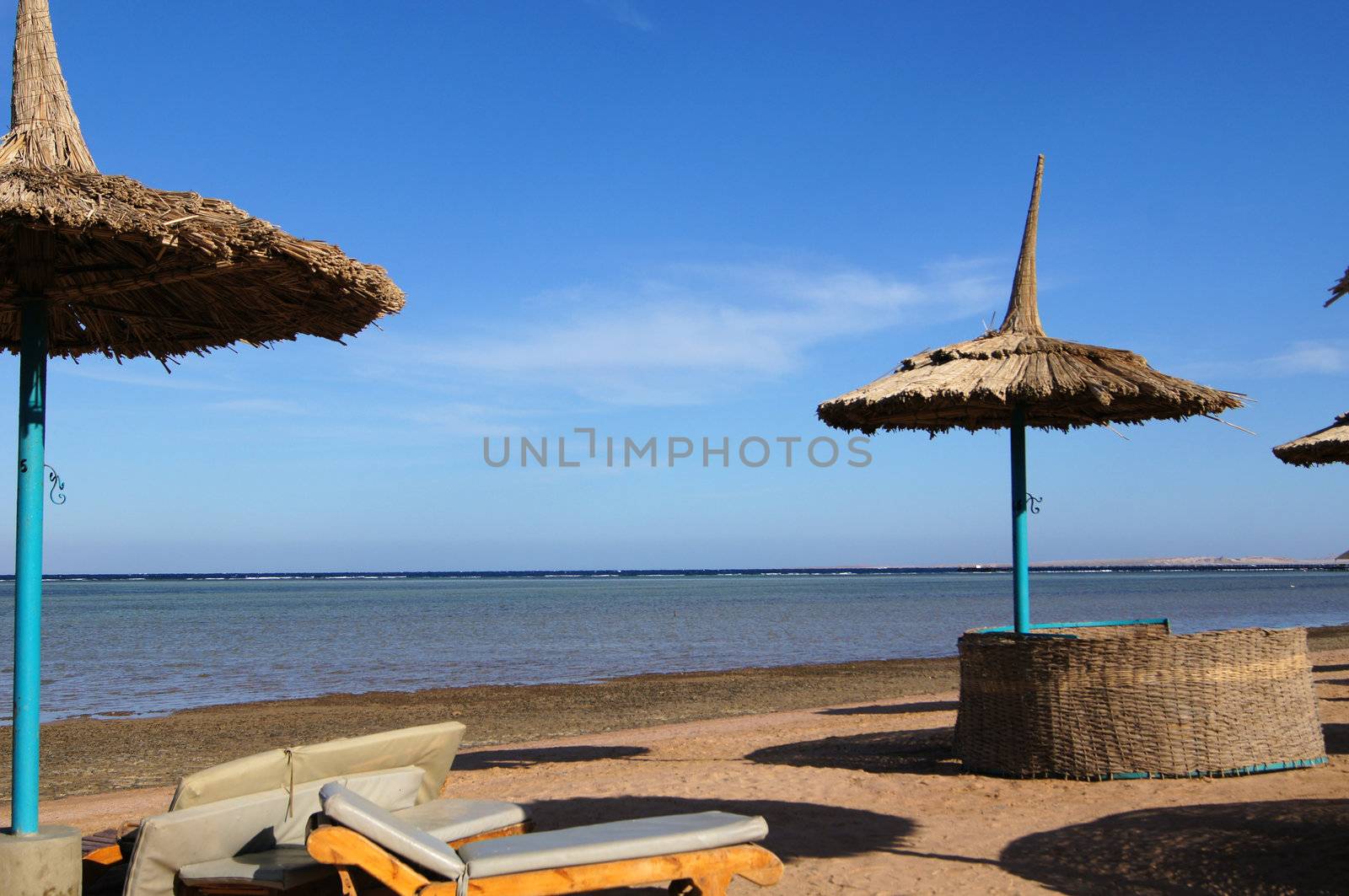 Sun umbrellas and beds on the sand beach                   