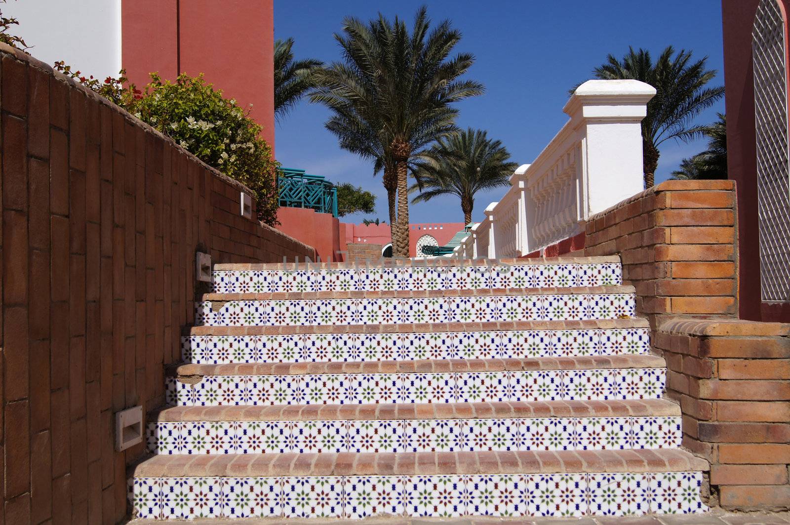 Courtyard of mediterranean villa with ceramic tile walkway and blooming bushes in Egypt                