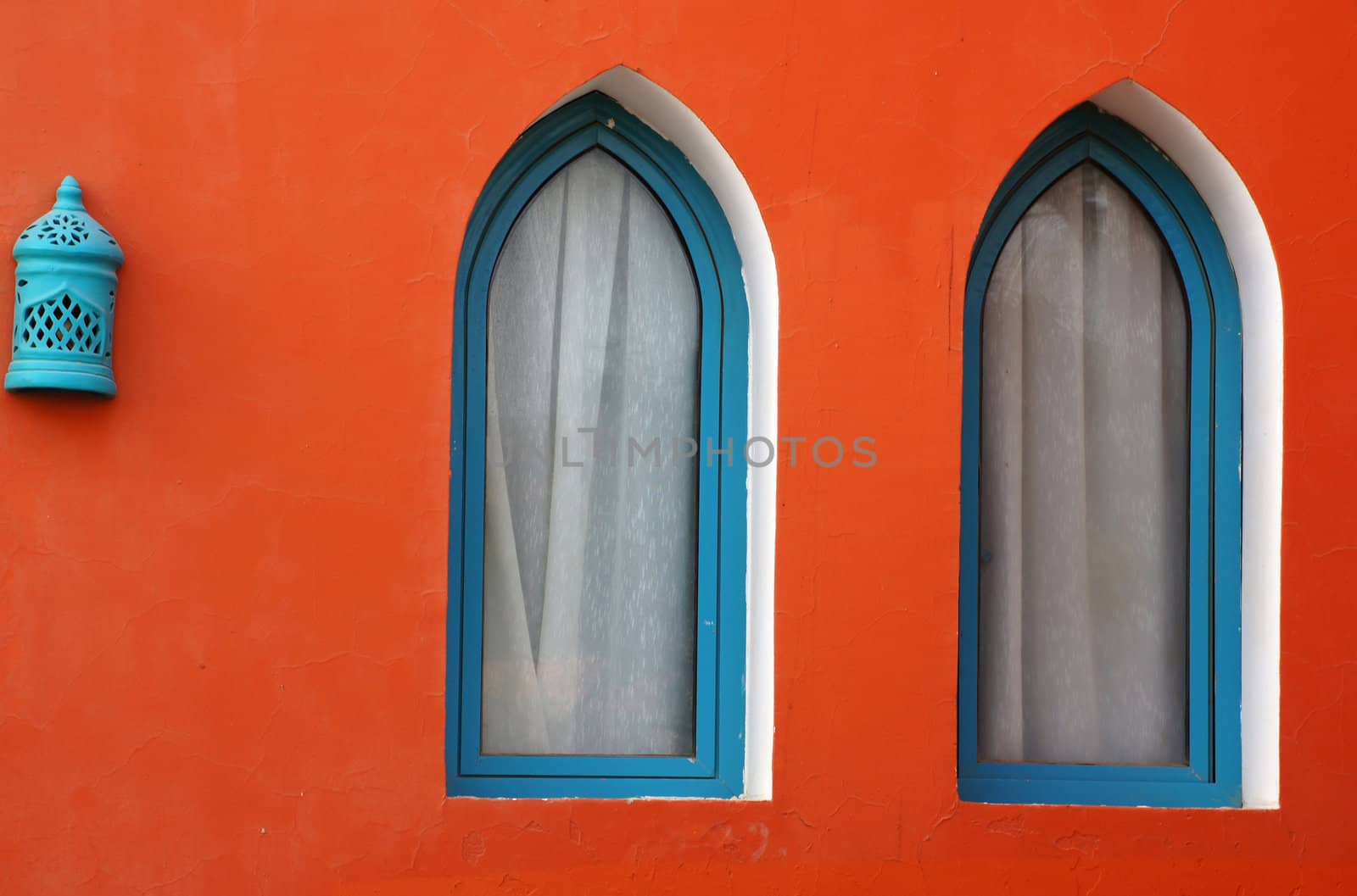 Arabic architecture: two windows and lamp on the red wall            