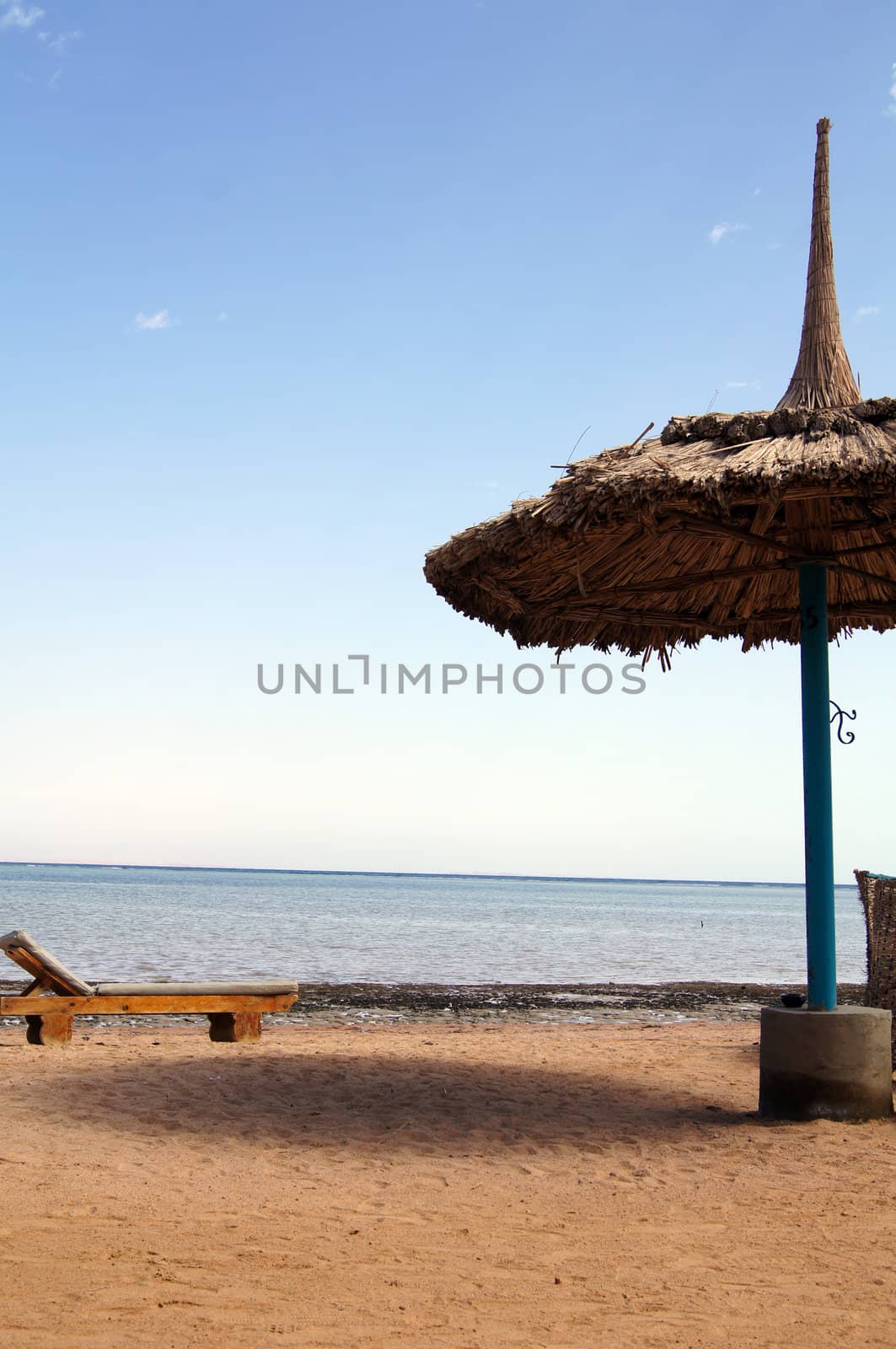 Sun umbrella, beach bed and sea             