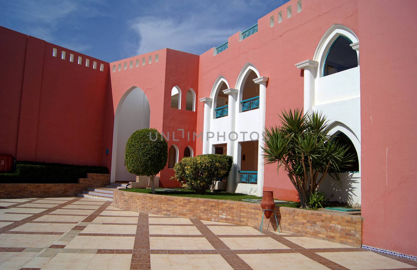 Arabic architecture: Courtyard of mediterranean villa with ceramic tile walkway and blooming bushes in Egypt        