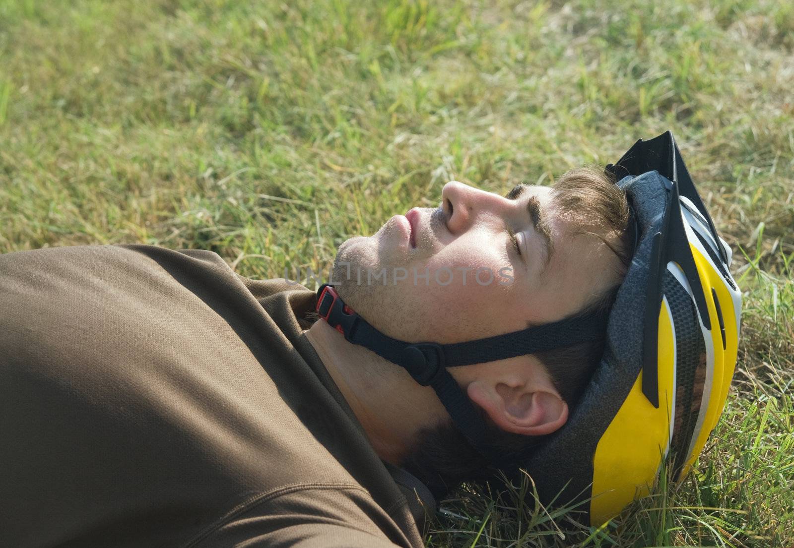 Young cyclist lying on a ground with eyes closed