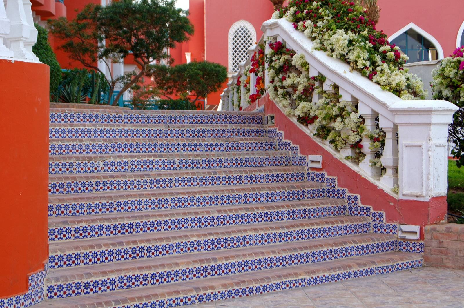 Courtyard of mediterranean villa with ceramic tile walkway and blooming bushes in Egypt           