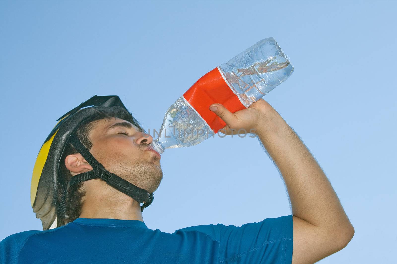 Young cyclist drinking water, view from below