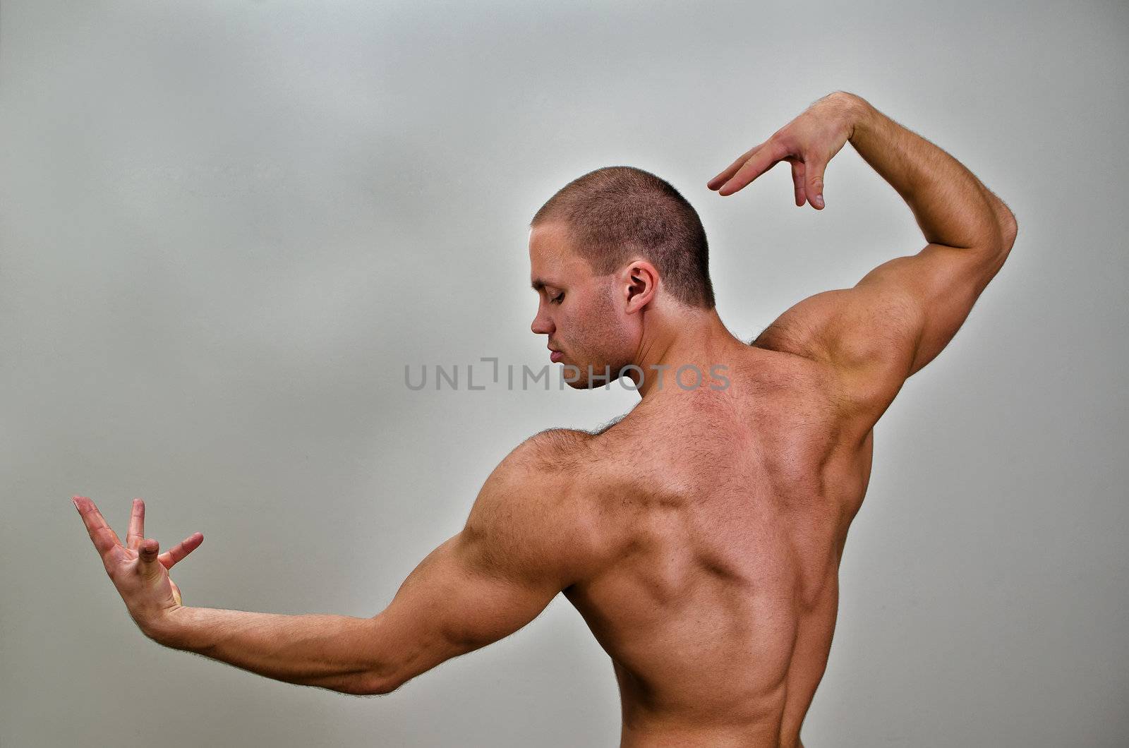 Muscular bodybuilder posing. On grey background.