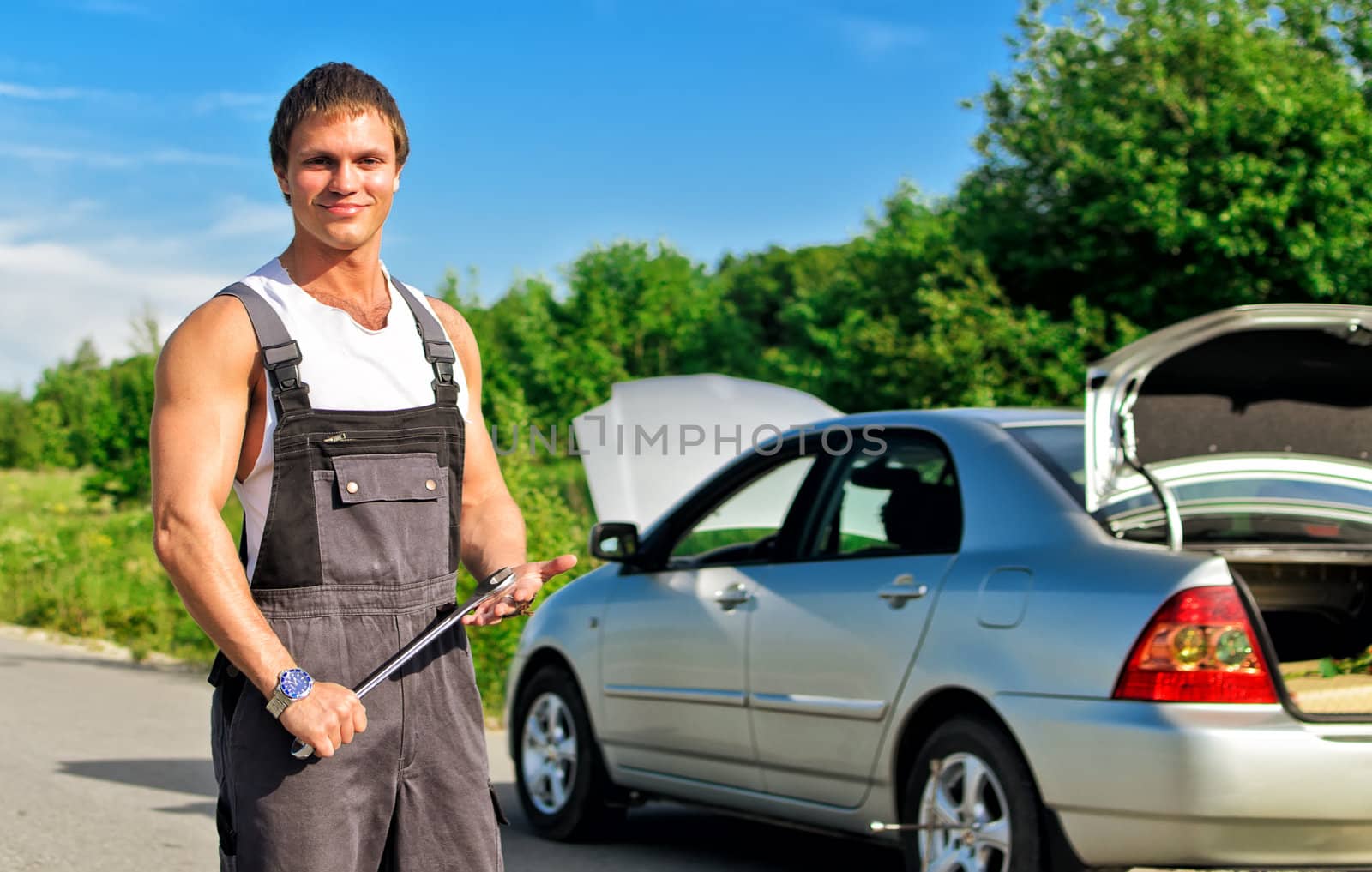 Handsome mechanic on a road near the broken car