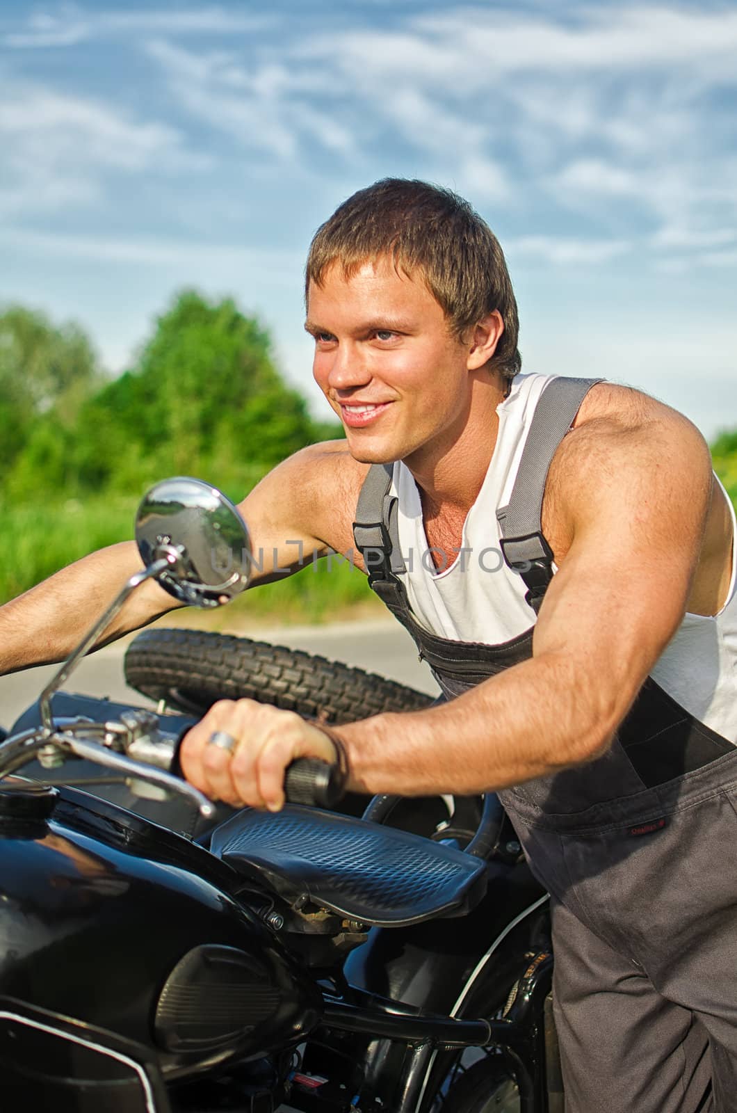 Portrait of handsome mechanic pushing a motorcycle