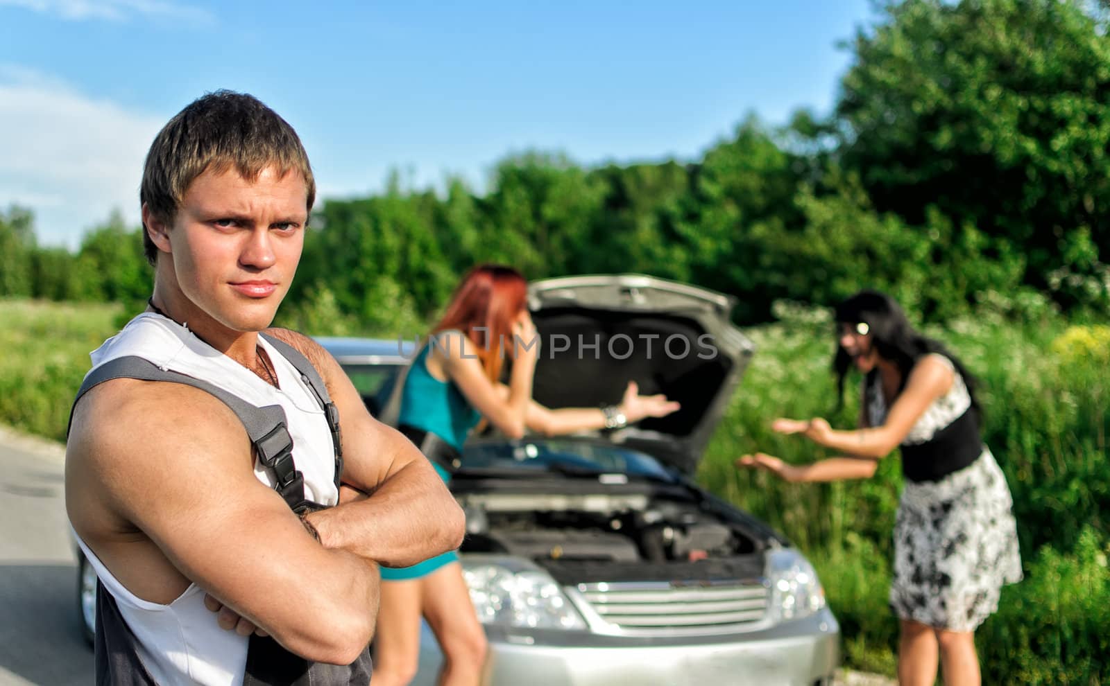 Portrait of a hadsome mechanic with two women on a background