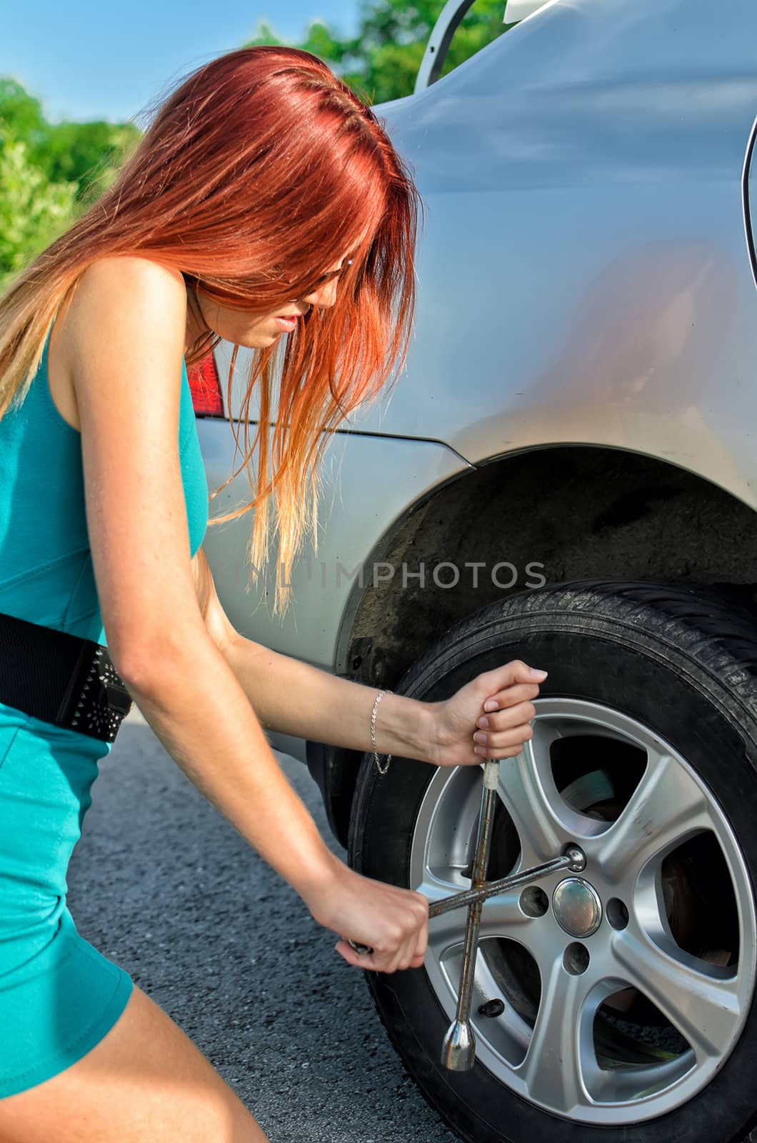 Pretty girl removing a wheel on a road by dmitrimaruta