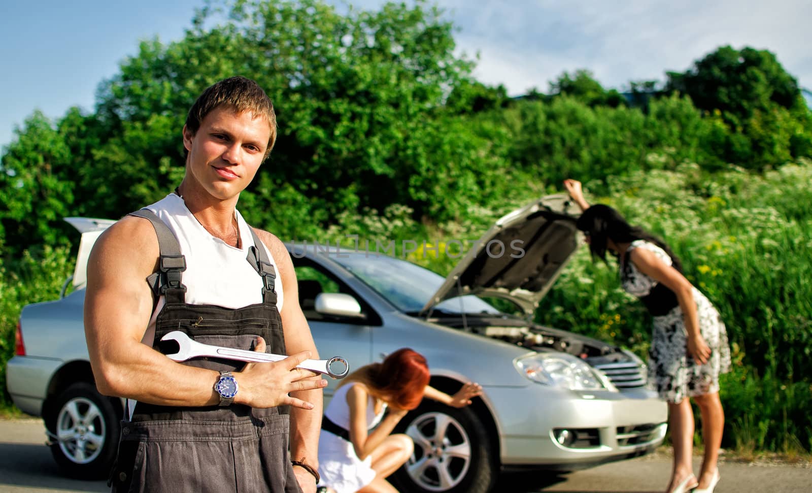 Portrait of a hadsome mechanic with two women on a background
