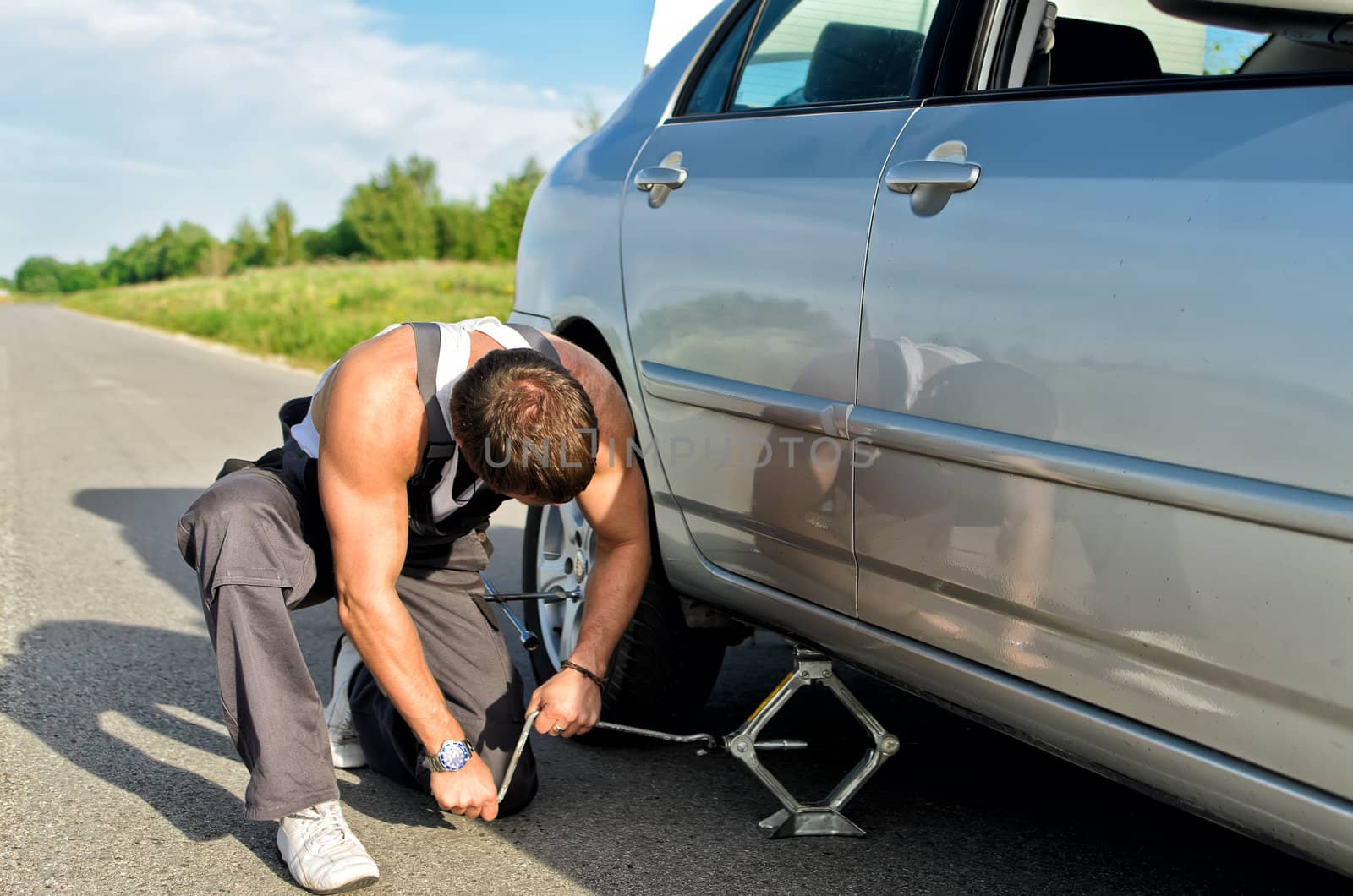 Mechanic lifting a car with jack-screw by dmitrimaruta