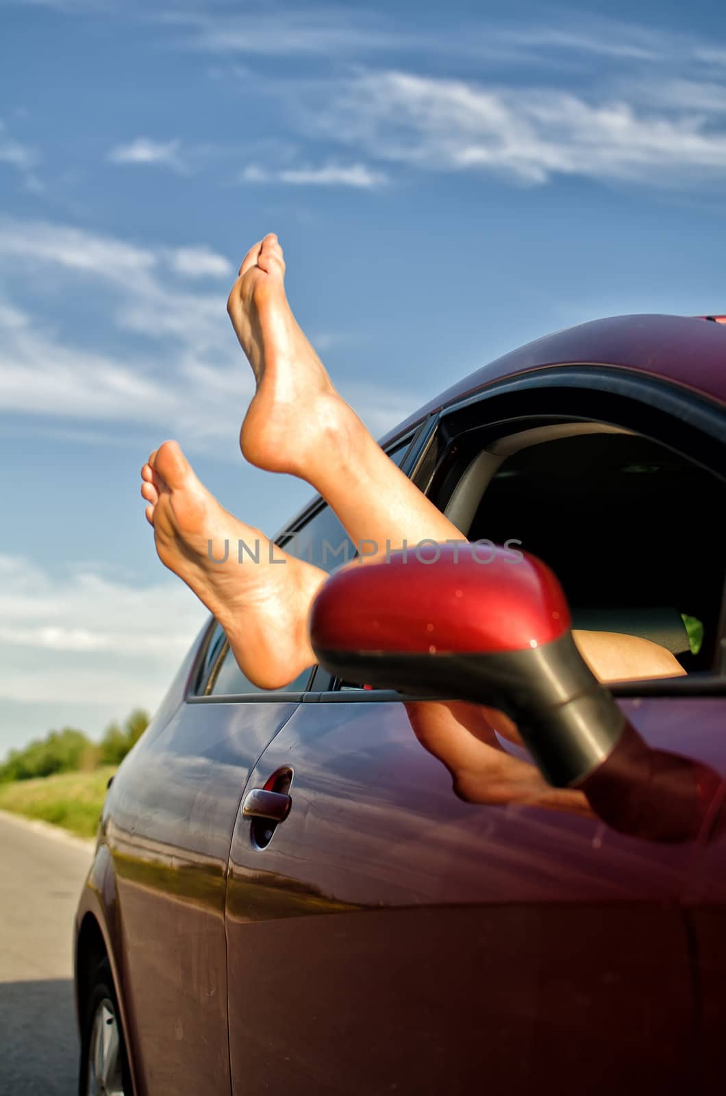 Woman's legs out of the car window. Concept of carefree funny trip.