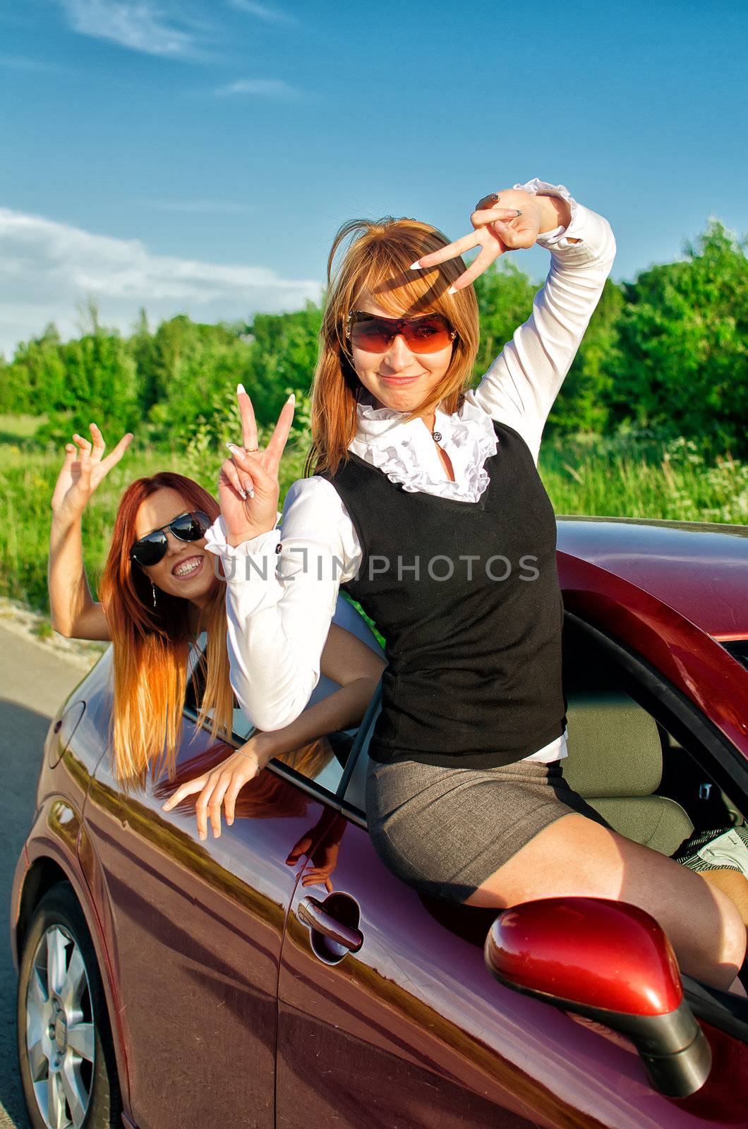 Two pretty happy girls in the car. Concept of carefree roadtrip by dmitrimaruta