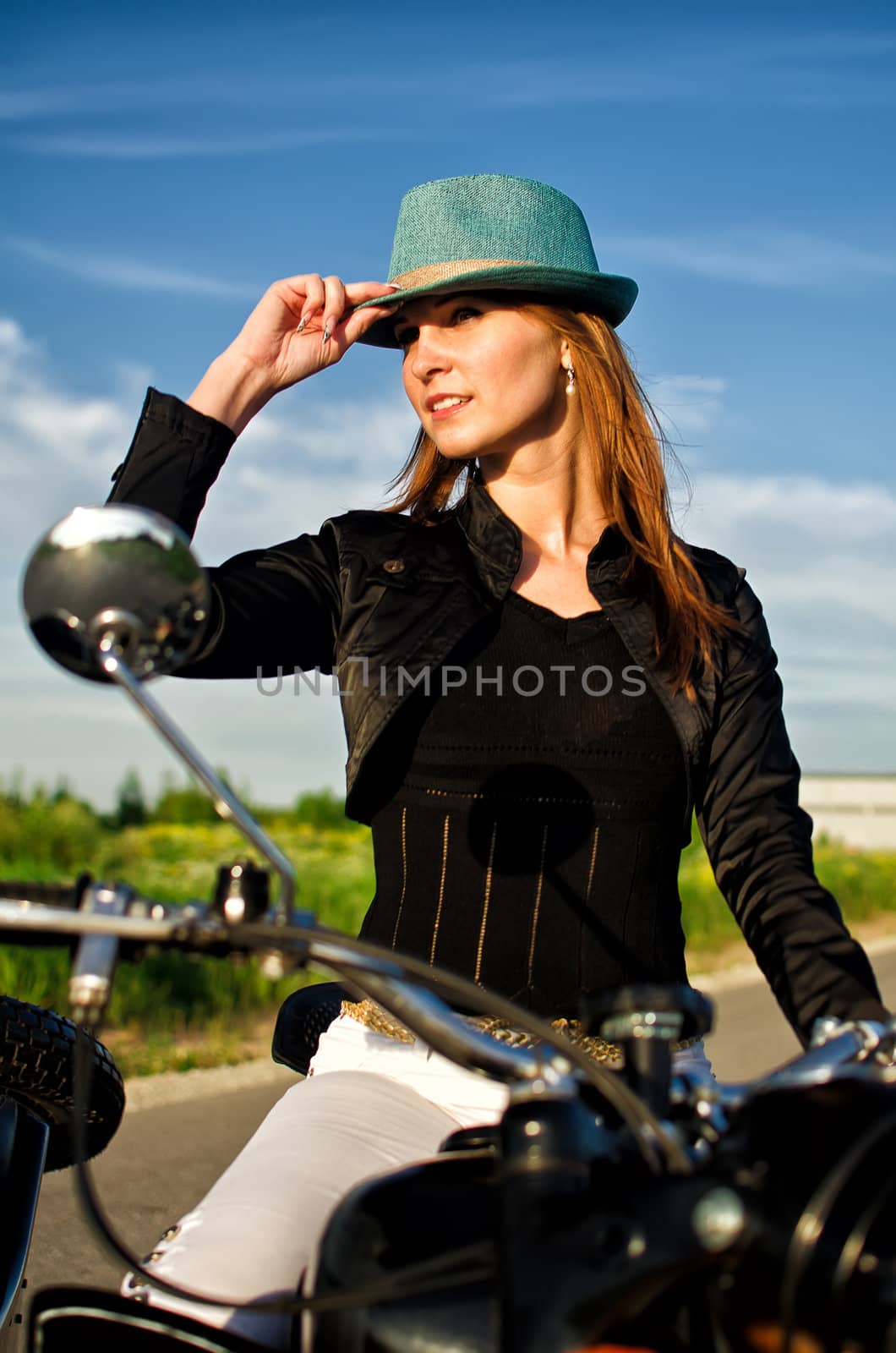 Portrait of a sexy lady in a hat sitting on motorcycle