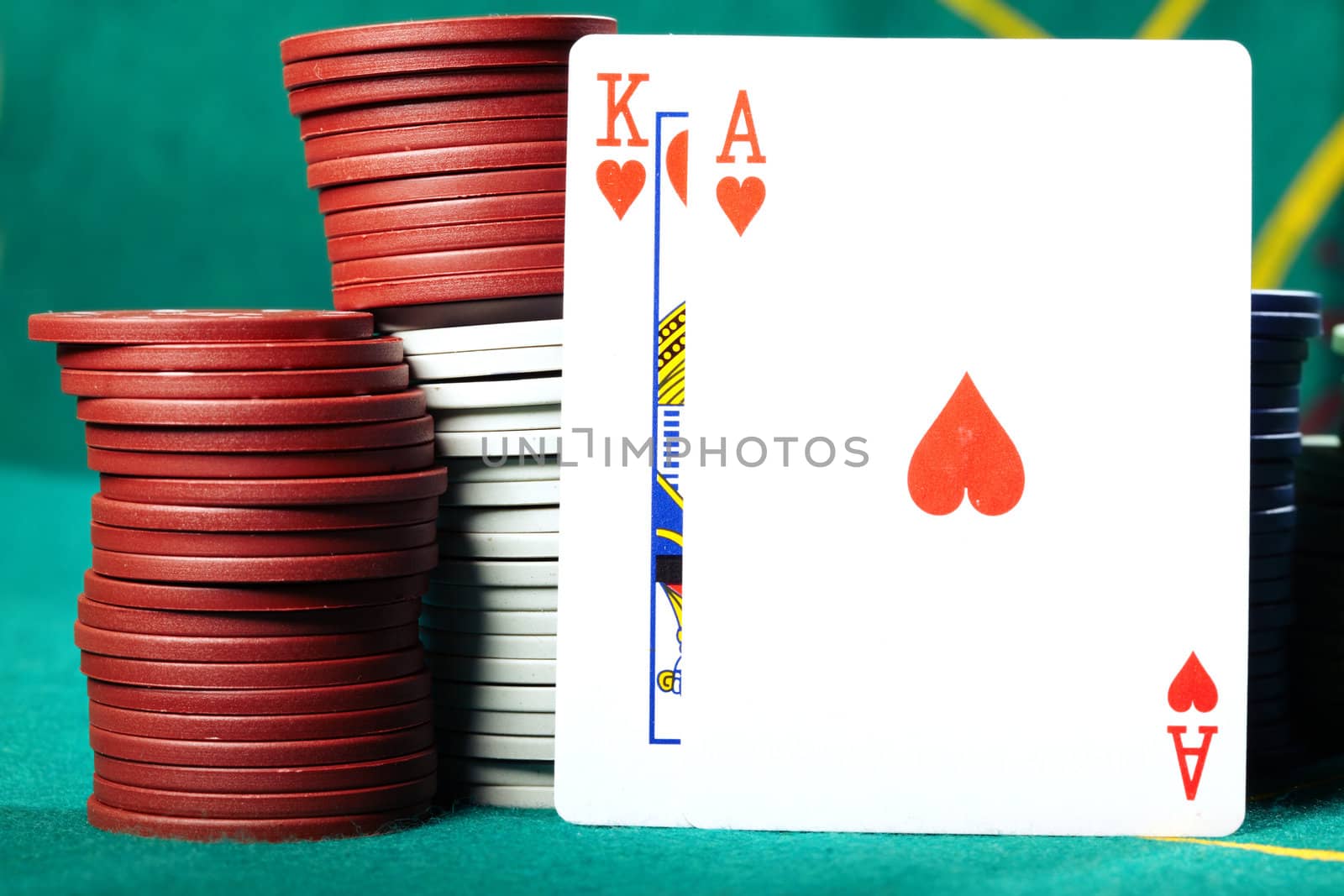 King and ace placed near the poker chips on a green table in casino. Close-up photo with natural colors
