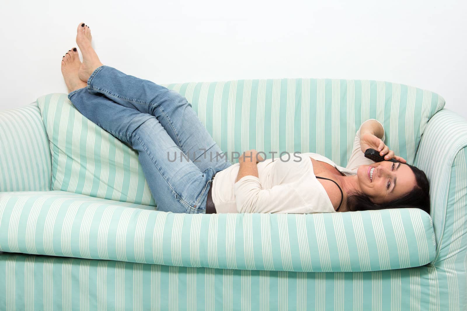 Black Haired Woman Talking On Phone while lying on couch