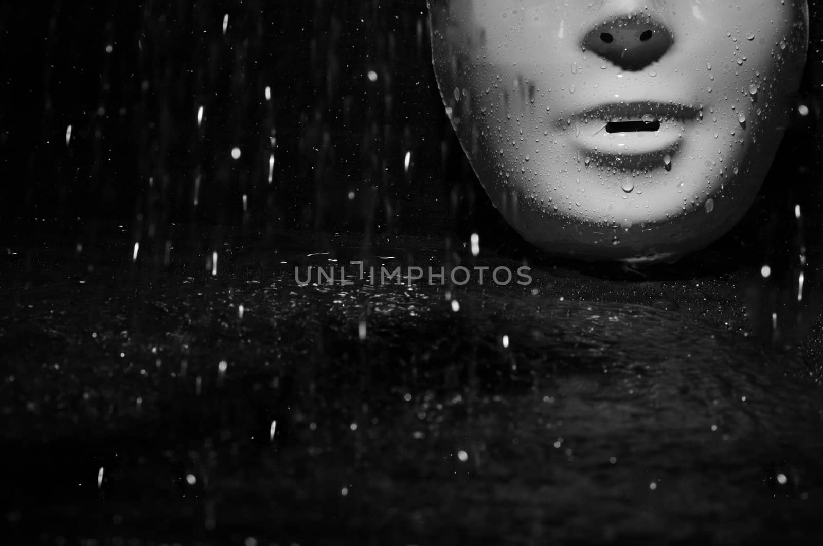 Plastic mask under the rain on a dark background