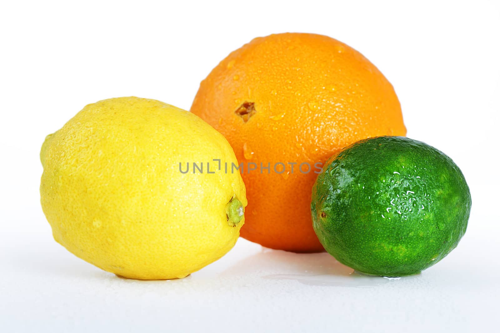 Beautiful studio still life of whole wet citrus fruits, orange, lemon and lime on white table, perfect background for nutrition, diet, healthy eating, organic or other food concept.
