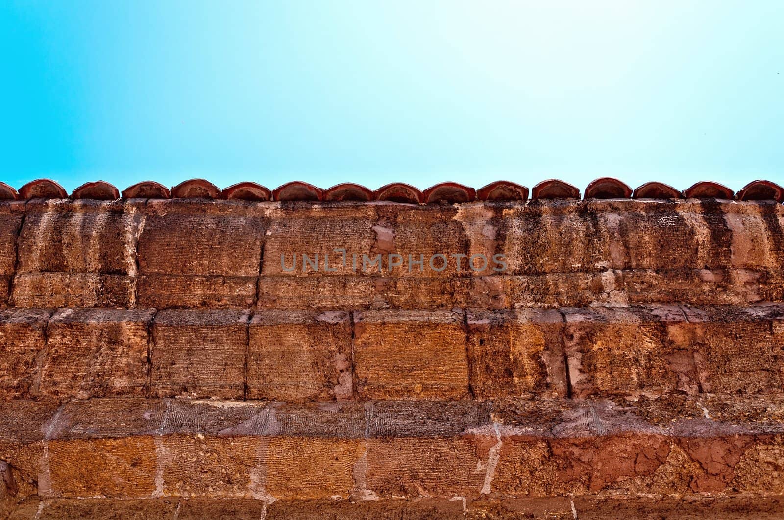 A fragment of an old weathered fence with a tiled cover.