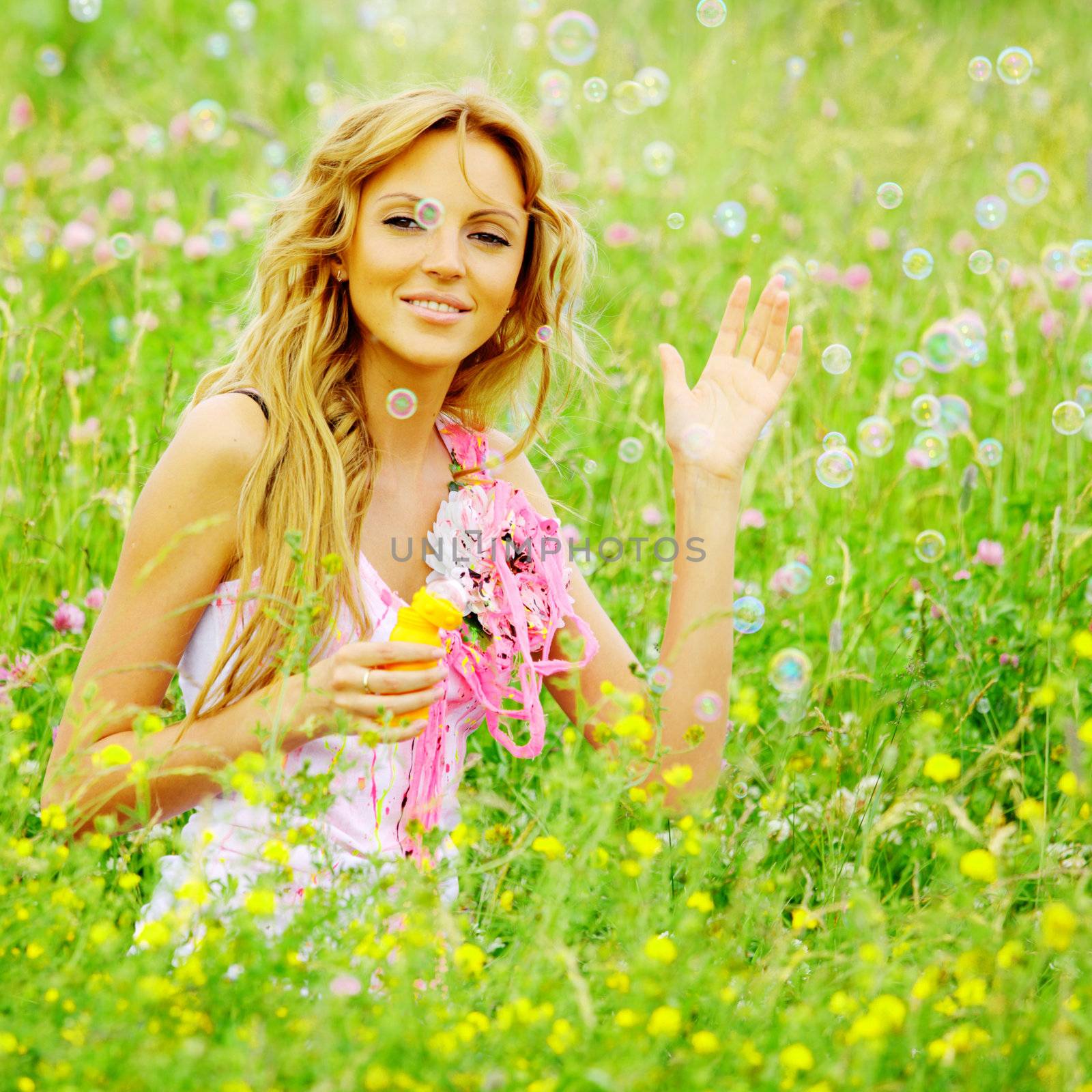  Blonde starts soap bubbles in a green field