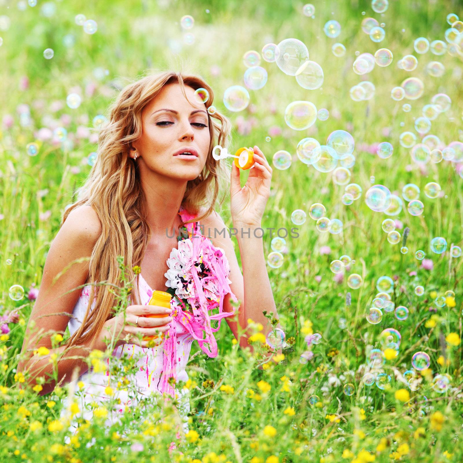  Blonde starts soap bubbles in a green field