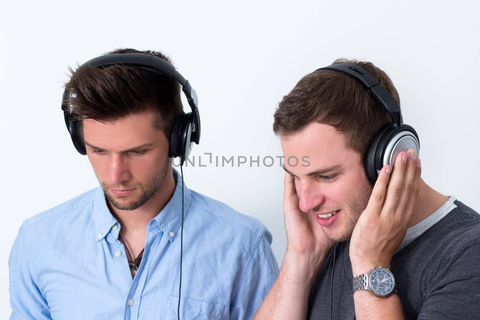 Two friends with headphone listening to music in front of a white background