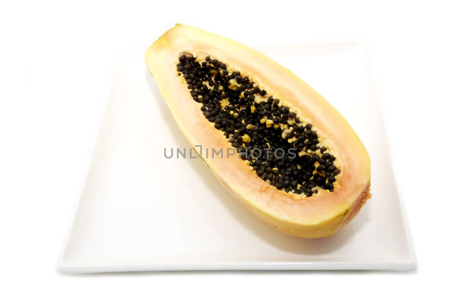 half of the papaya fruit on a plate on a white background