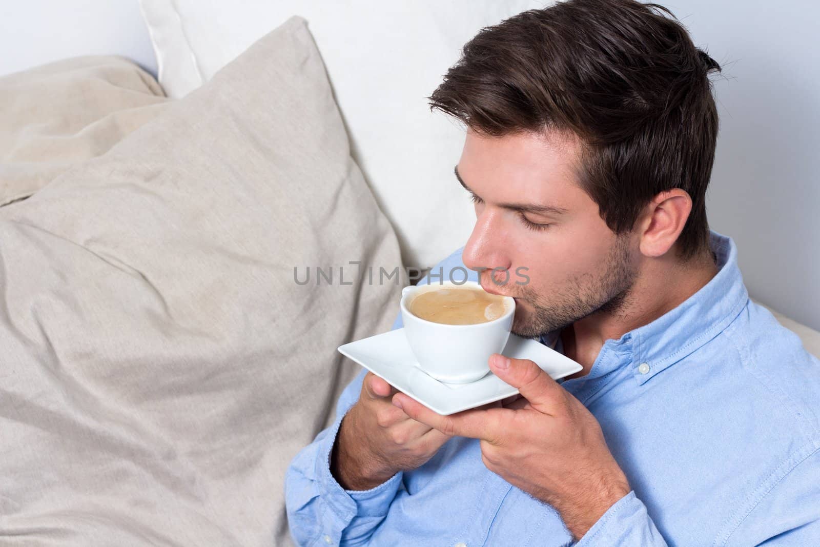 Young brunette man drinking coffee out of mug