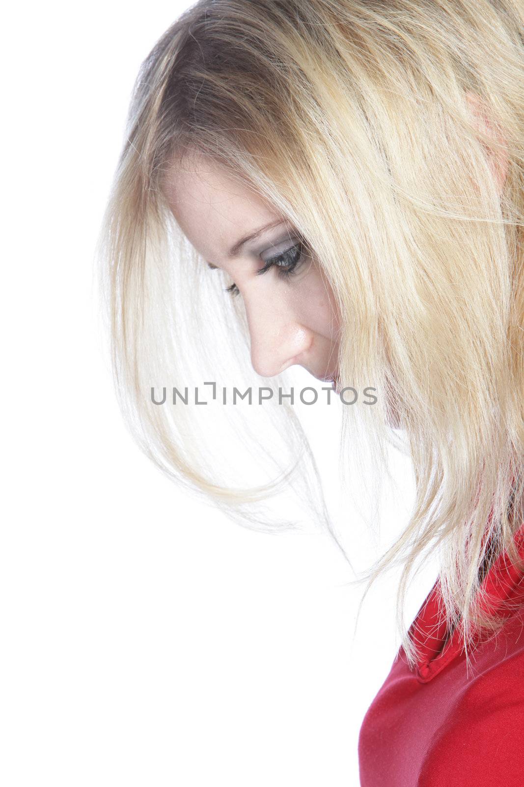 Closeup sideways portrait of the head of a dejected young woman looking down with her blonde hair partially obscuring her face