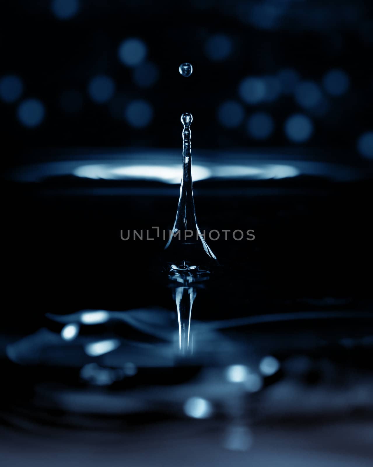 Extremely macro photo of the liquid drop falling on a dark background