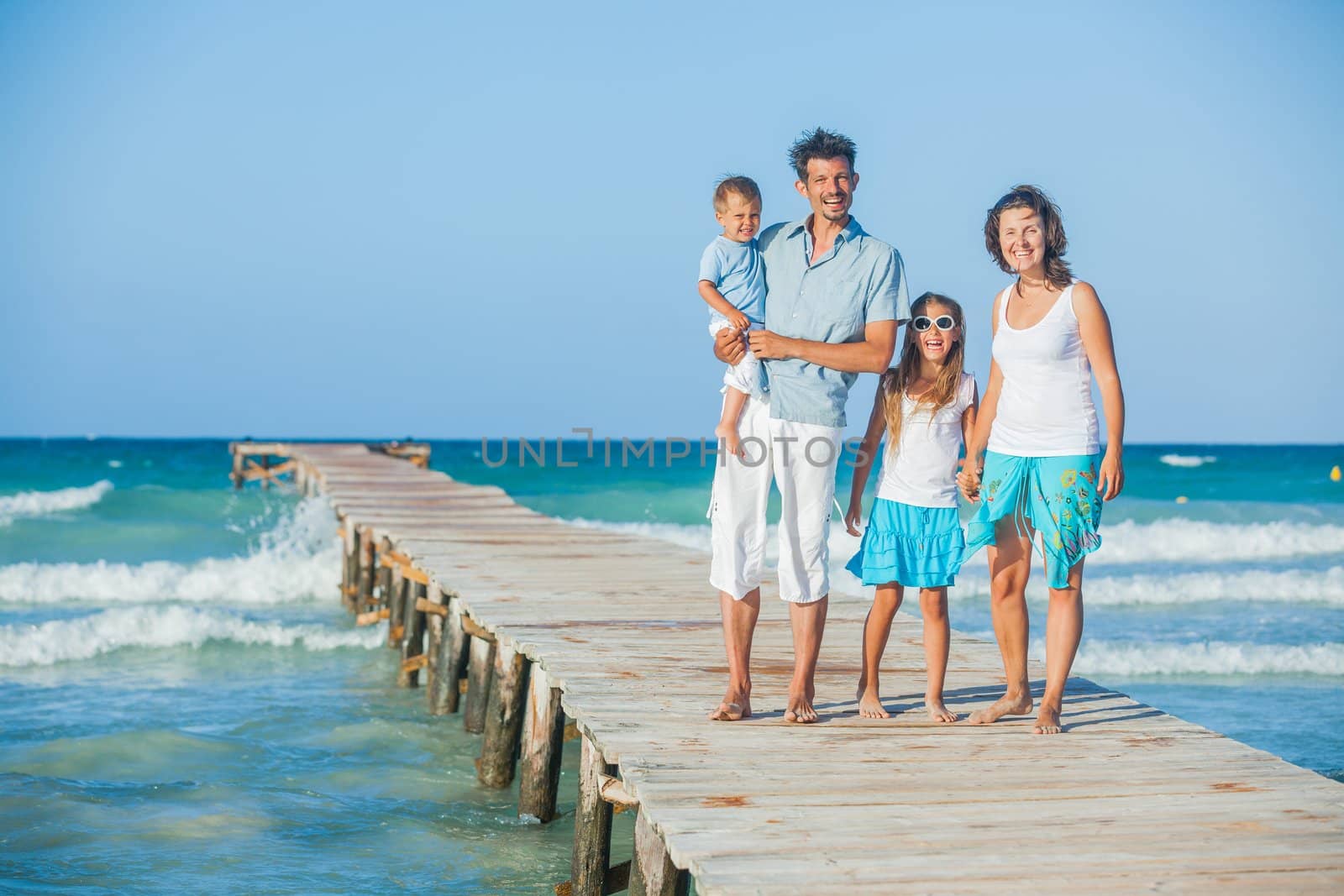 Family of four on wooden jetty by the ocean