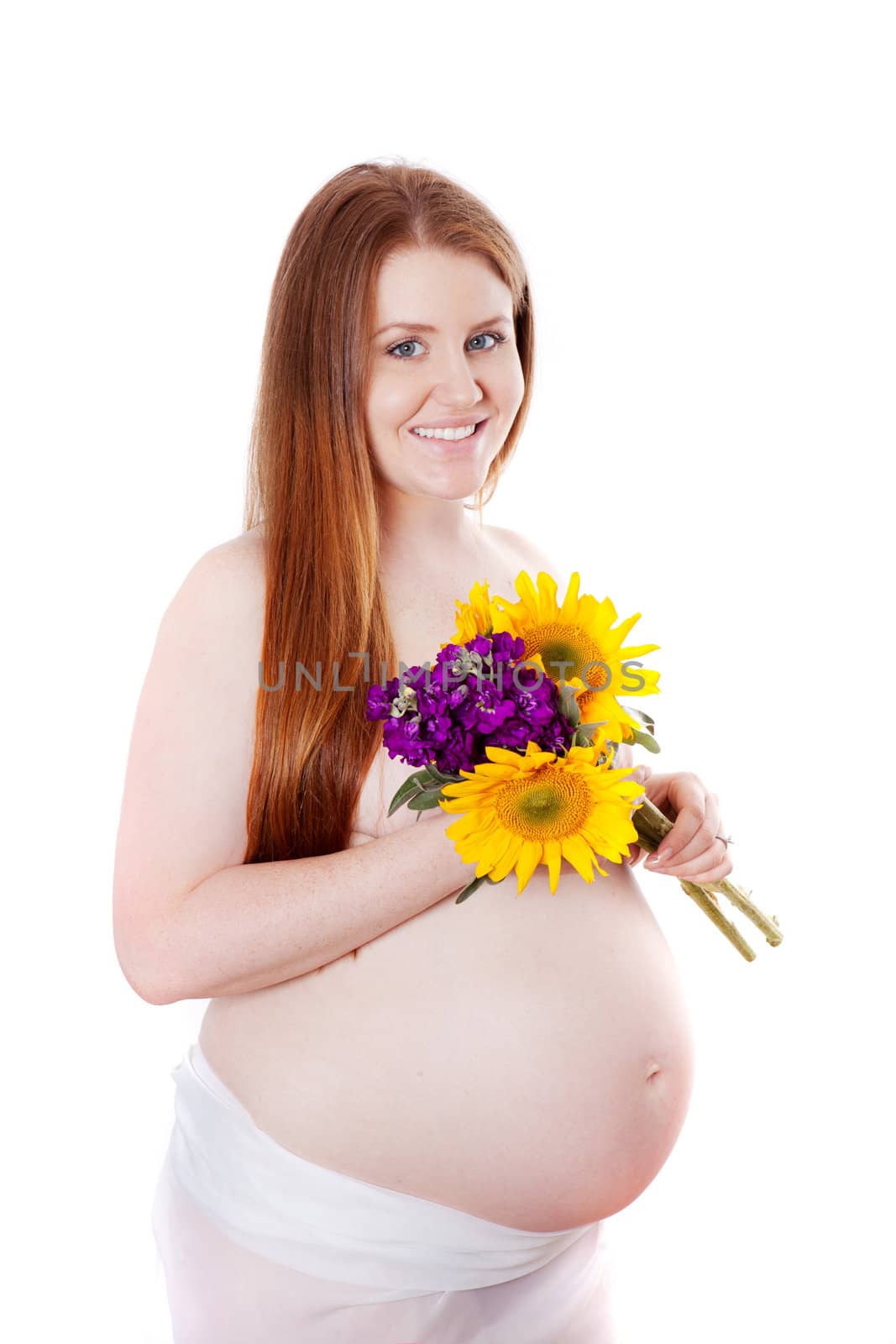 Beautiful pregnant woman holding flowers with long red hair