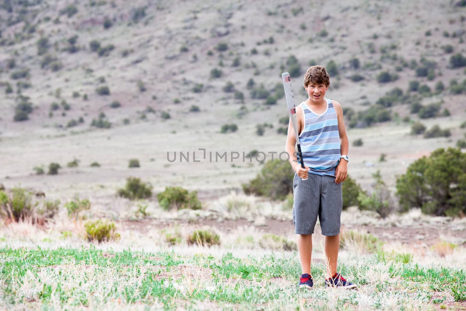 Teenager  Boy in a field with a Baseball Bat looking at camera