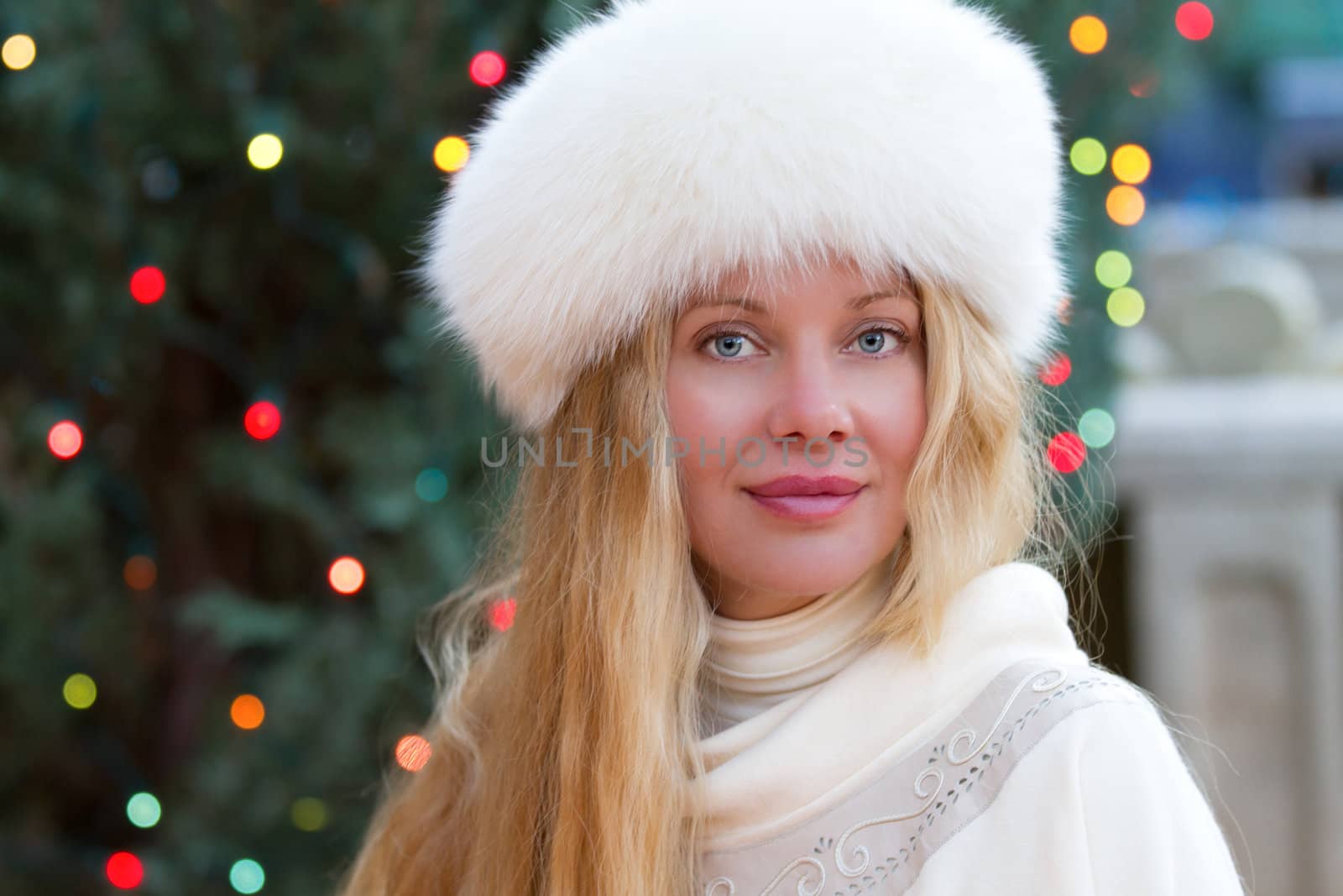 Pretty Blonde Woman wearing a White Fur Hat with Christmas Lights behind her