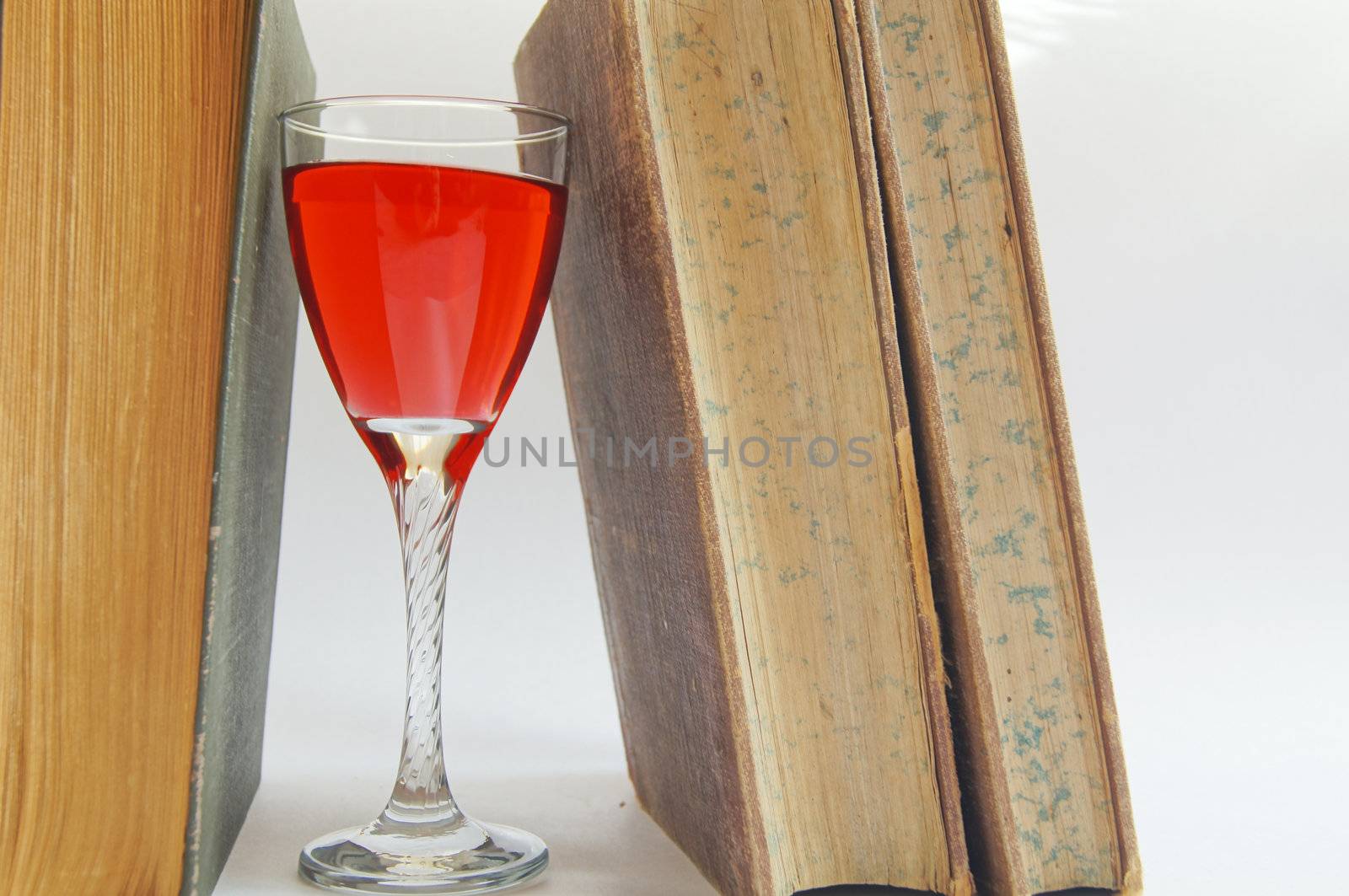 Old books and glass of rose wine