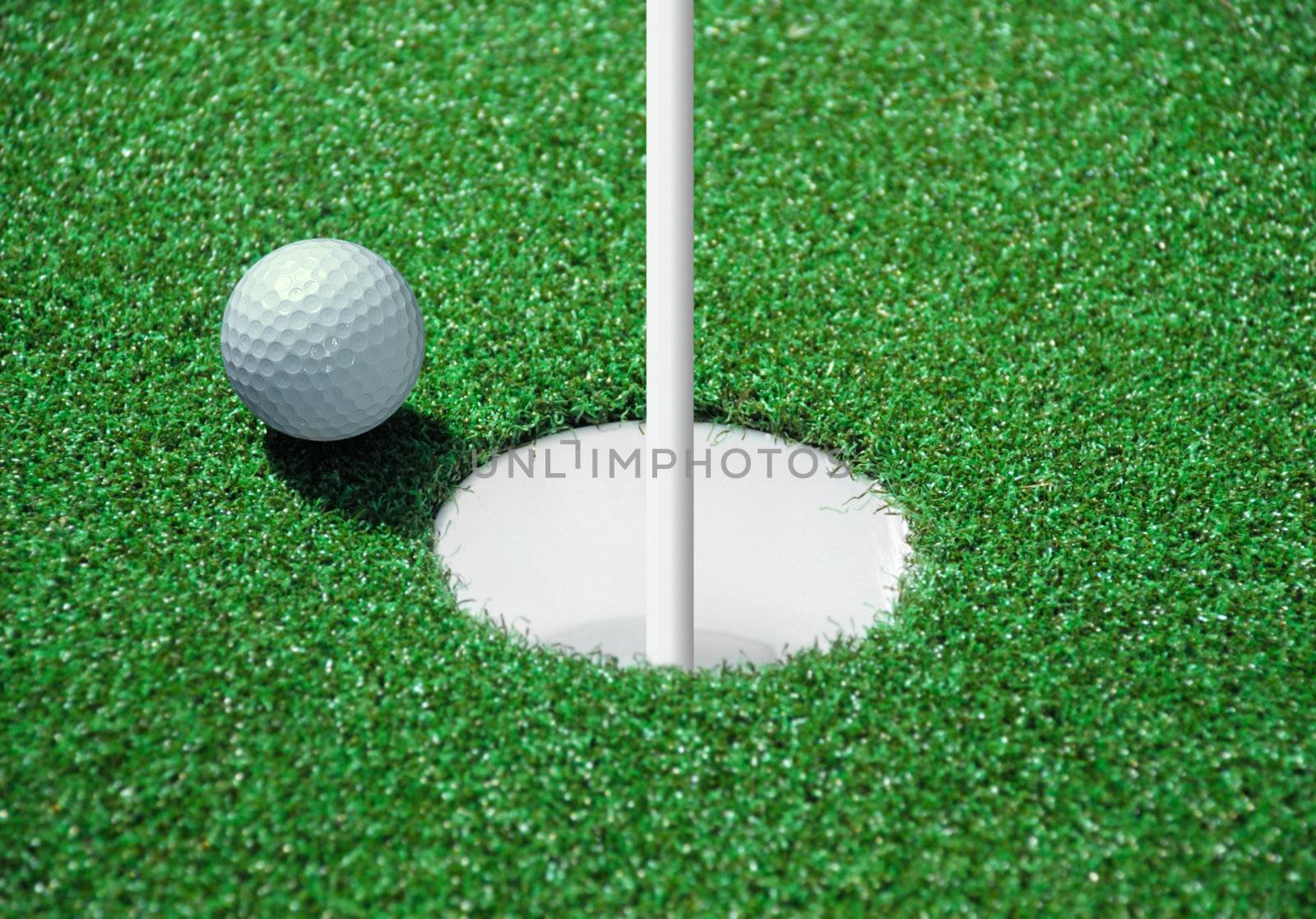 golf ball on lip of cup of lovely tropical golf course