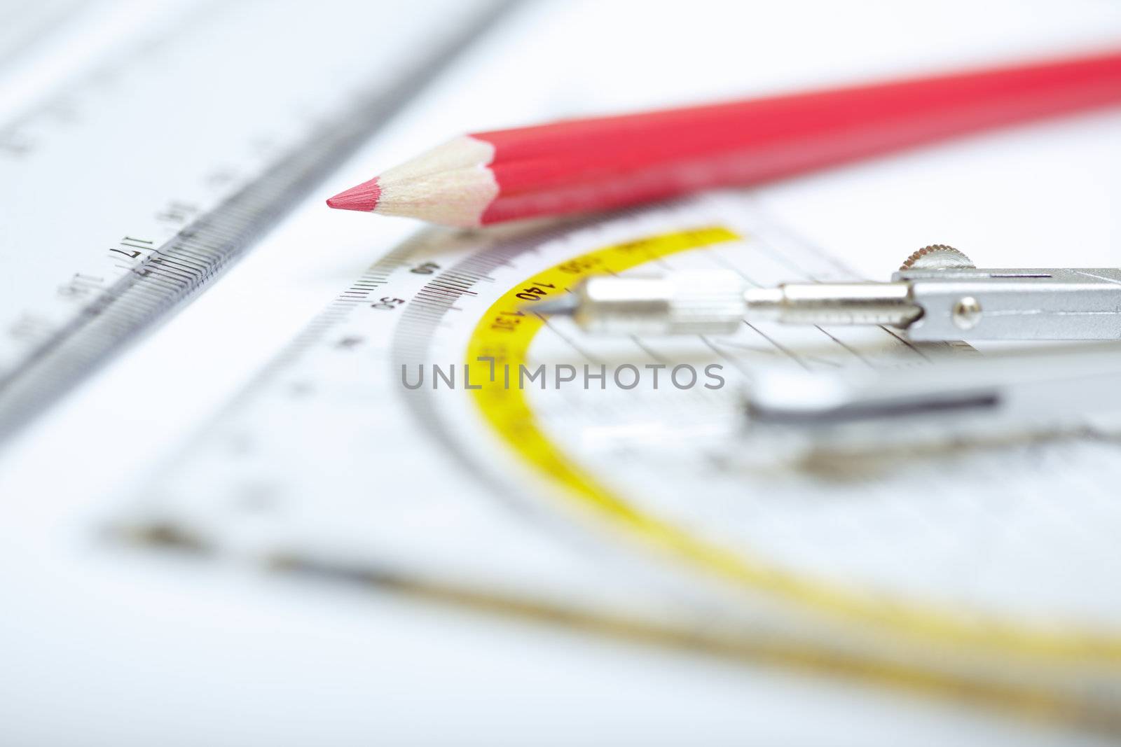 Red pencil with compasses and rulers on a paper. Extremely close-up photo