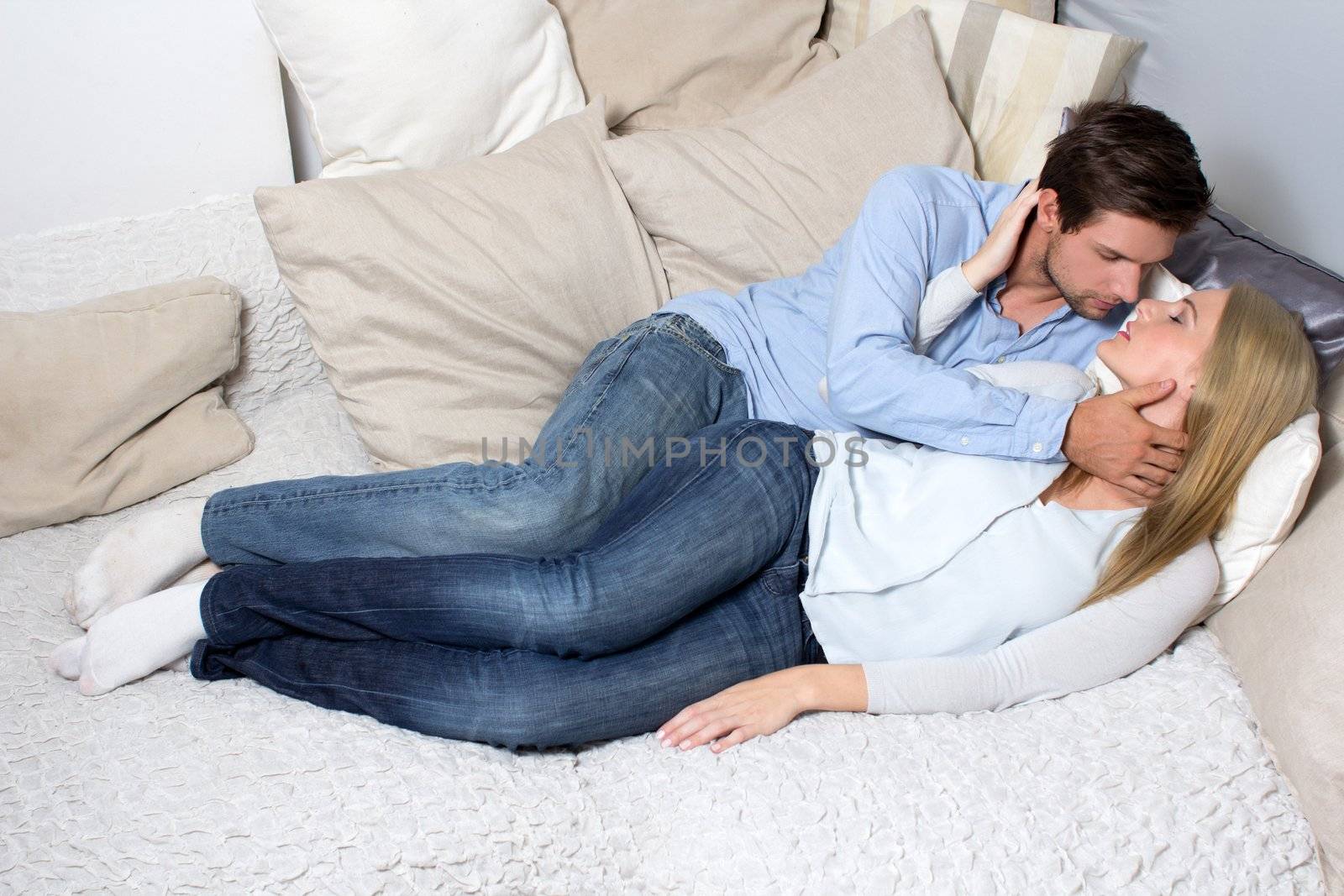Young Couple Kissing On A Couch by dwaschnig_photo