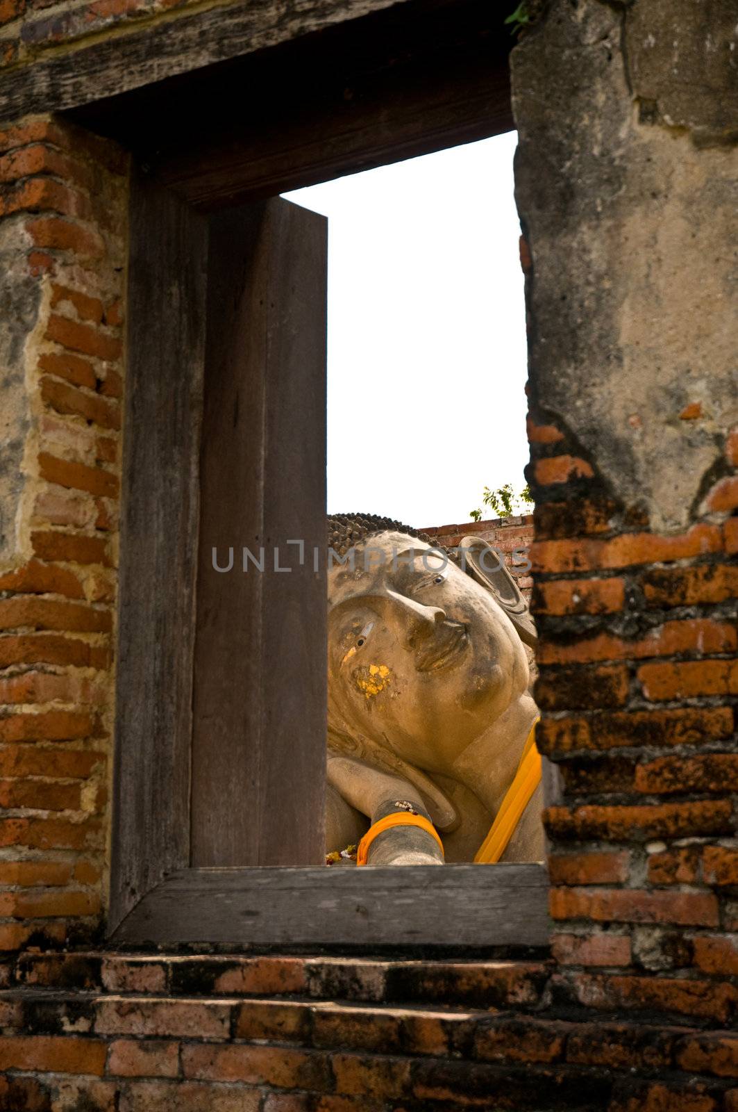 Reclining Buddha, view through a window with a wooden frame. Ayutthaya city is the capital of Ayutthaya province in Thailand. Its historical park is a UNESCO world heritage.