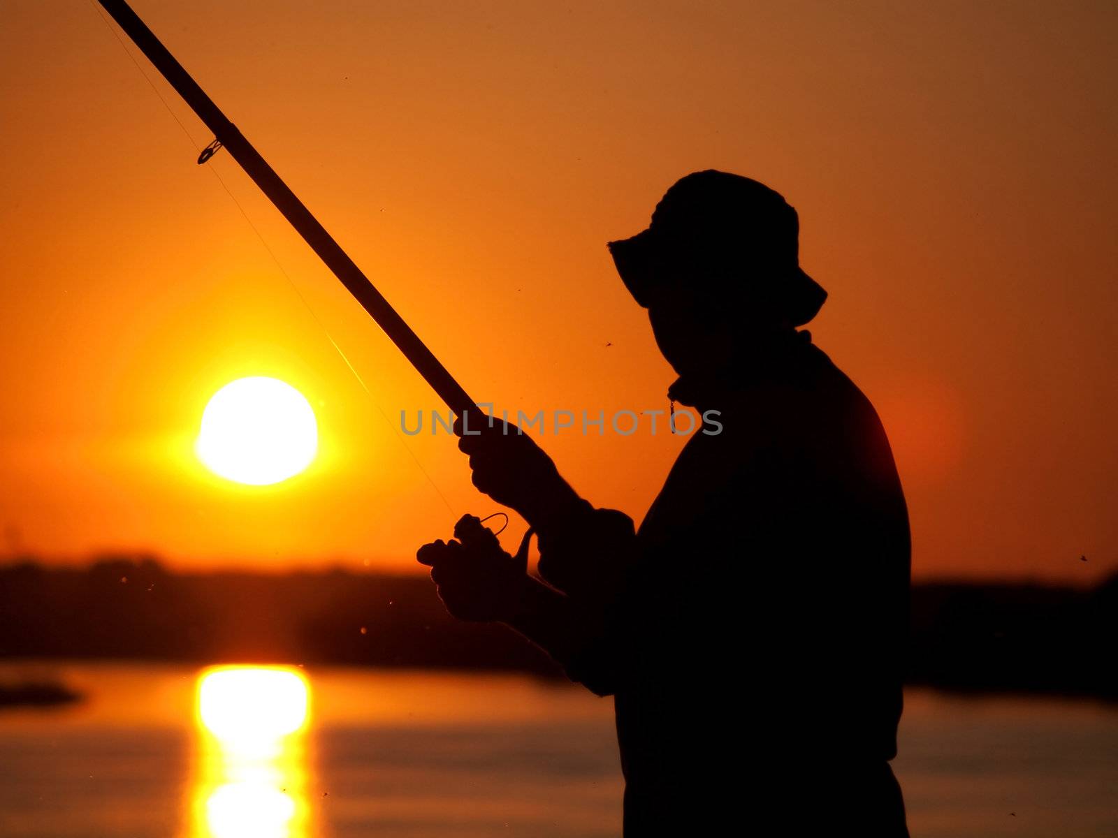 Silhouette of a fisherman on sunset 