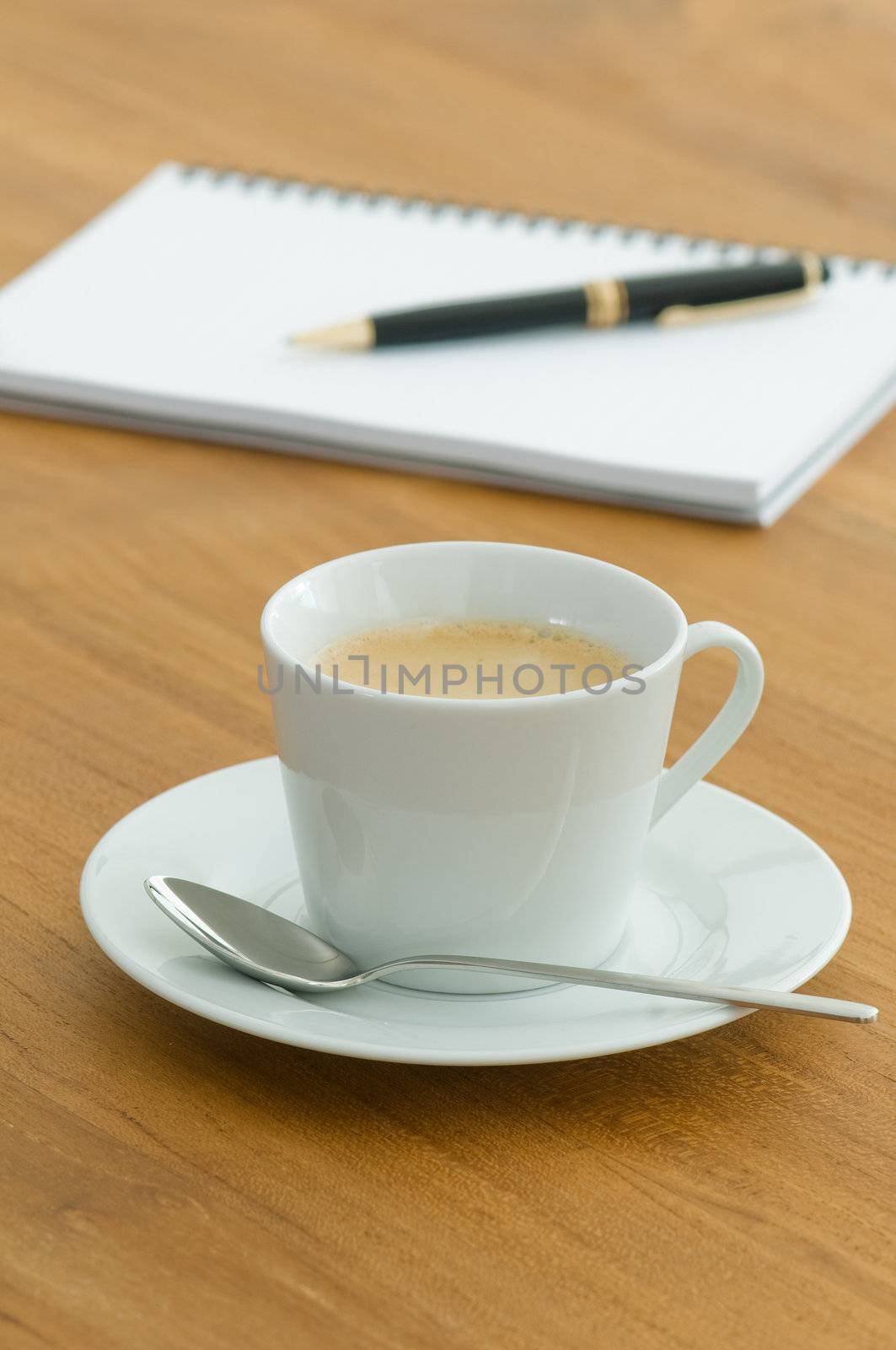 White coffee cup with writing utensils on a wooden table