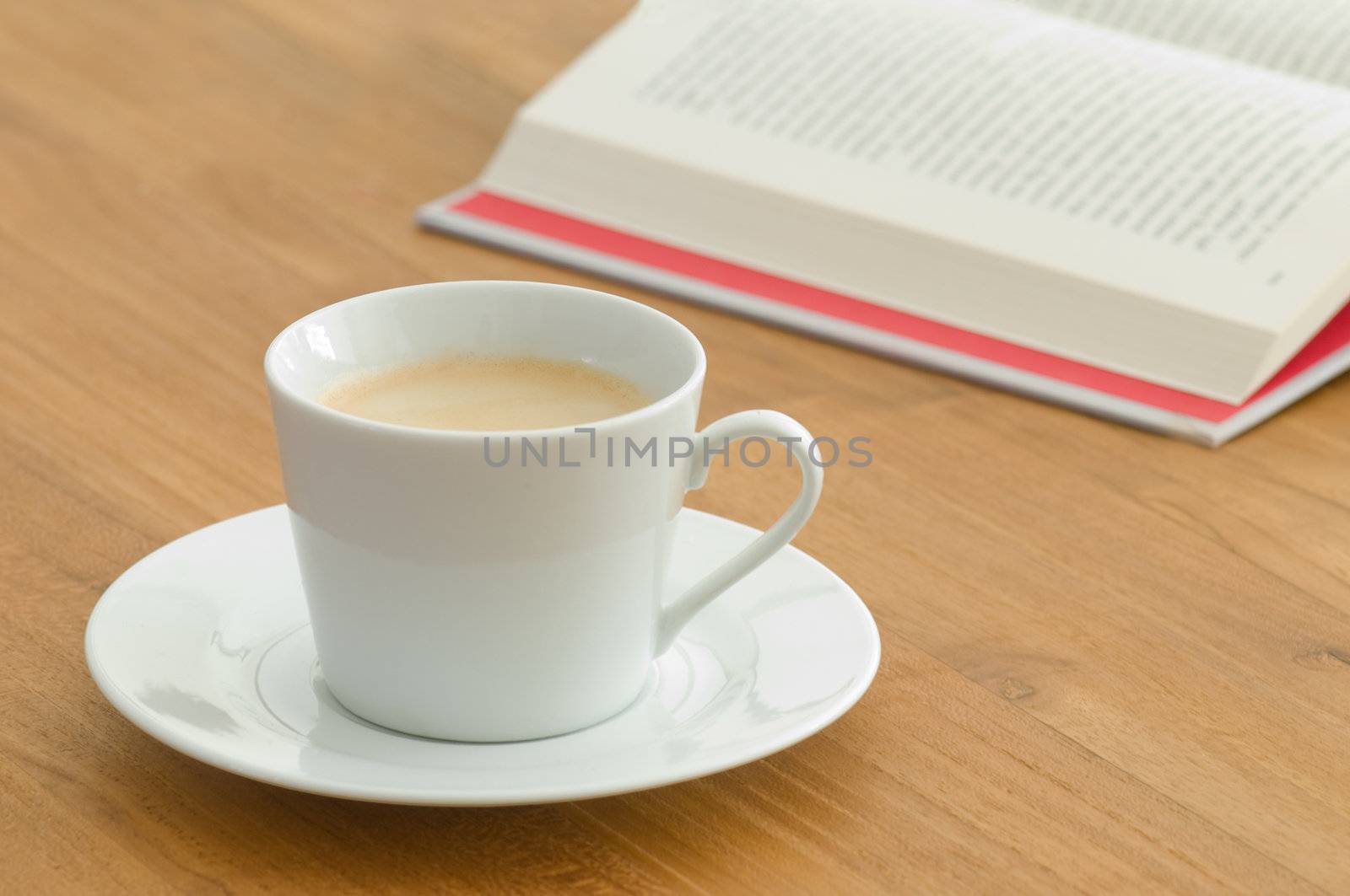 White coffee cup with open book on a wooden table