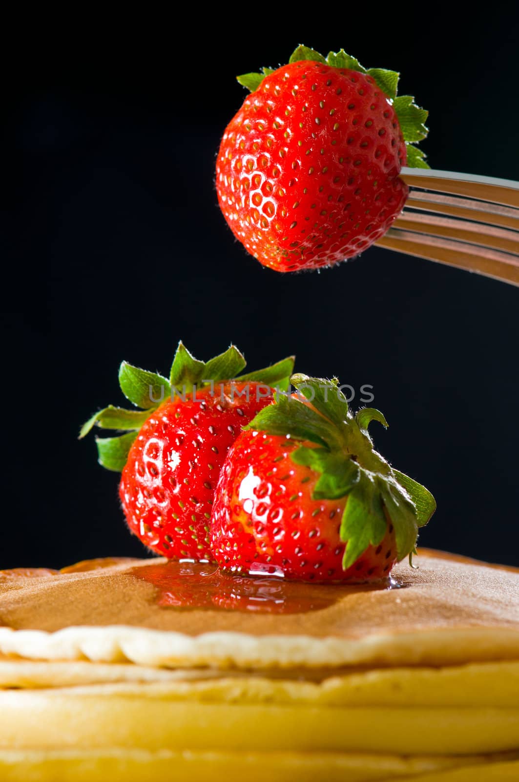 Strawberry butter pancake with honey/ maple sirup flowing down closeup shoot, one strawberry lifting up