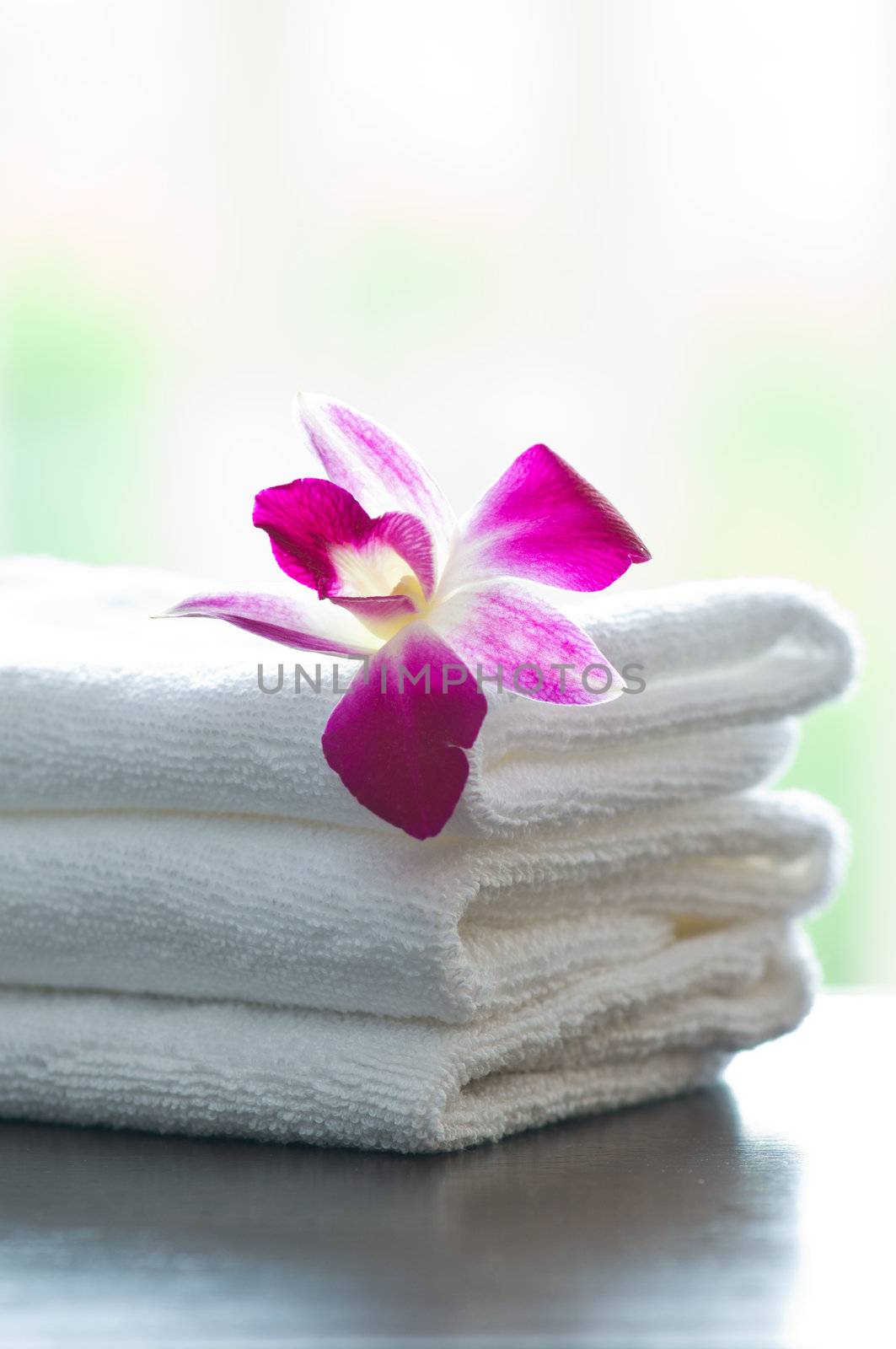 Spa towels and orchid flowers in front of a bright background