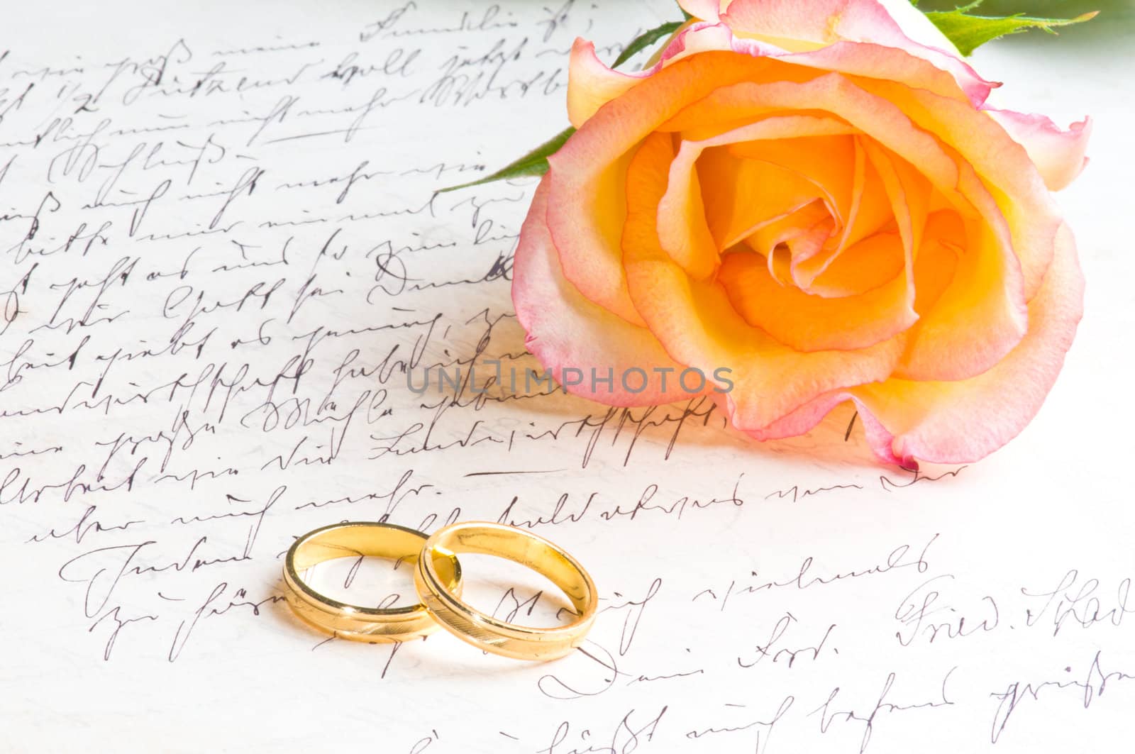 Rose and two rings over handwritten love letter