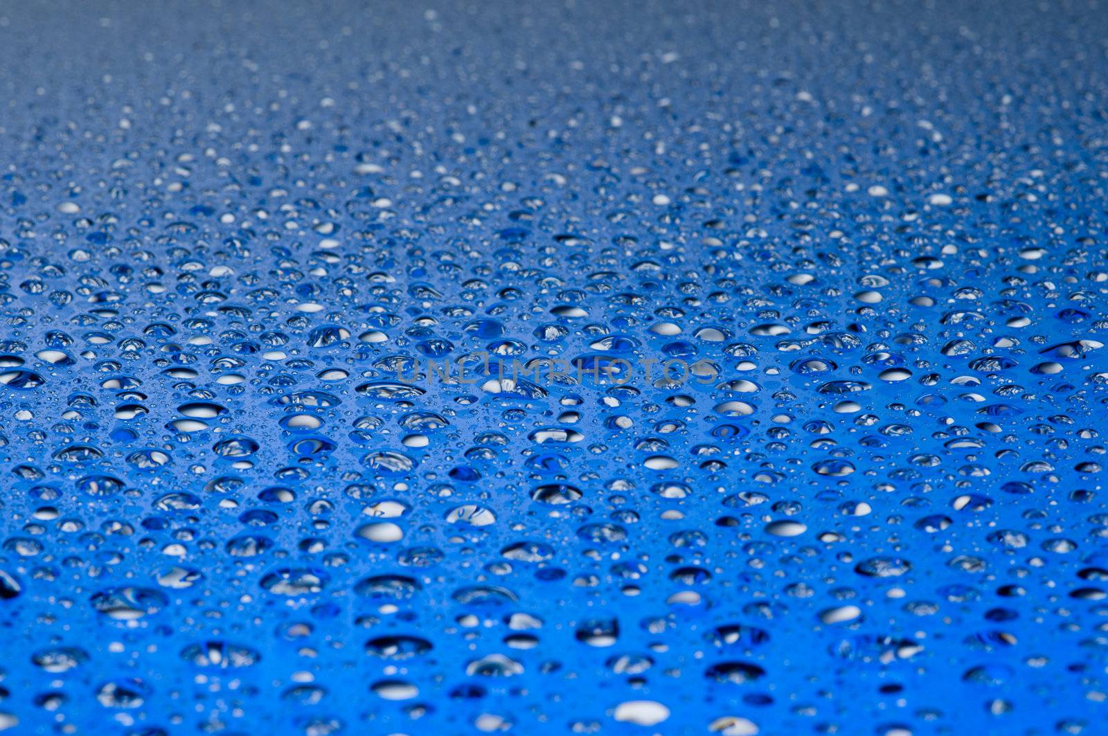 Water drops on a shiny surface in blue