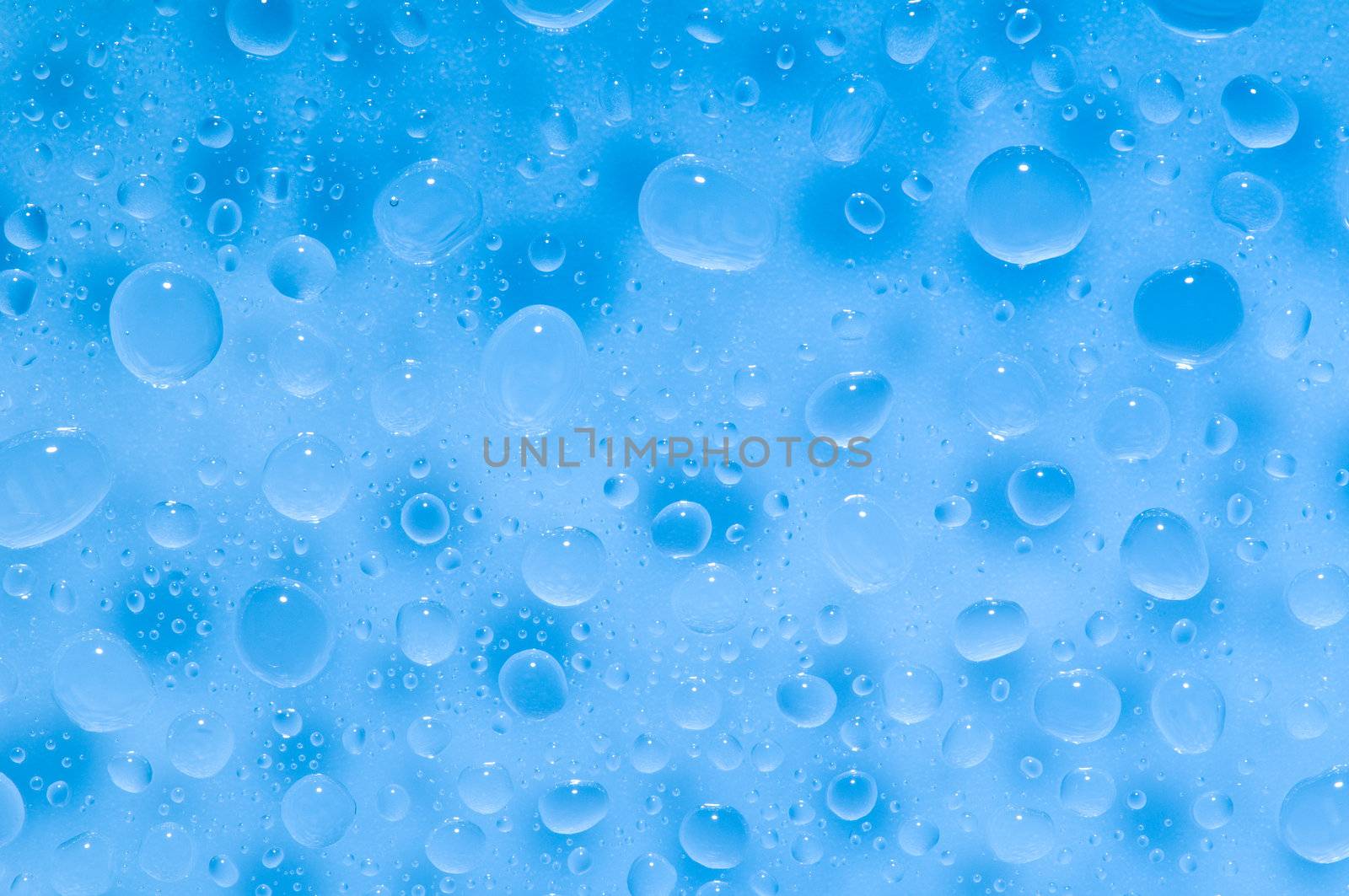 Water drops on a shiny surface in light blue