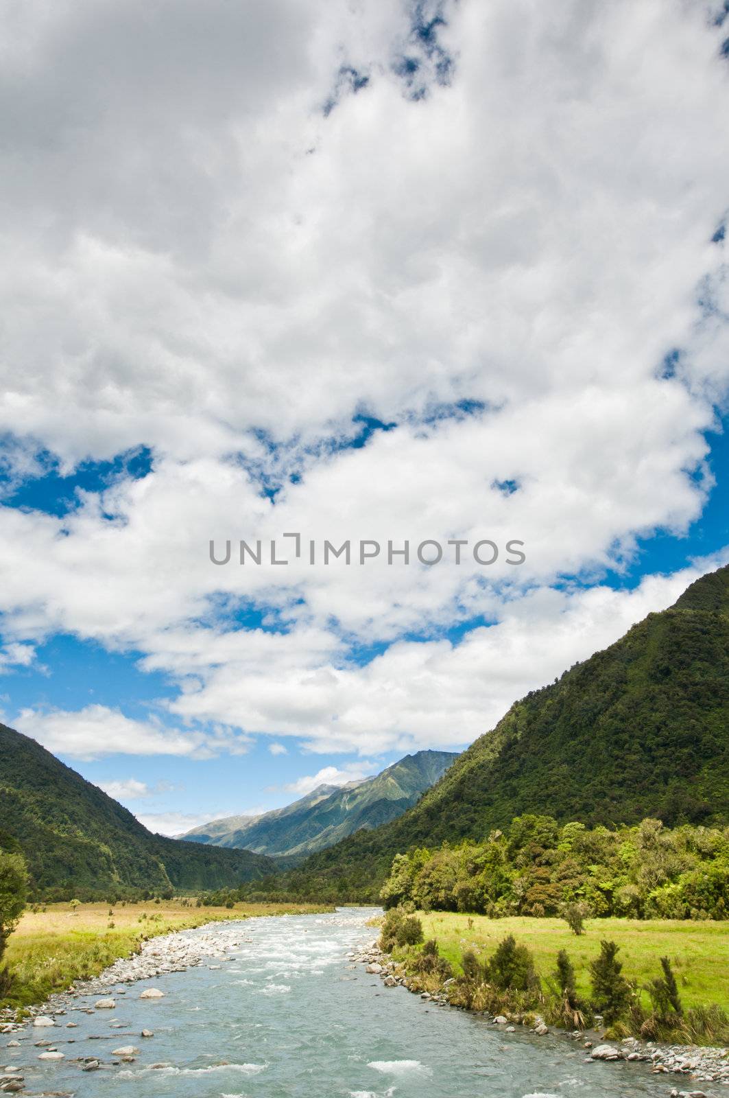 river flowing through a valley with massive cloudy sky
