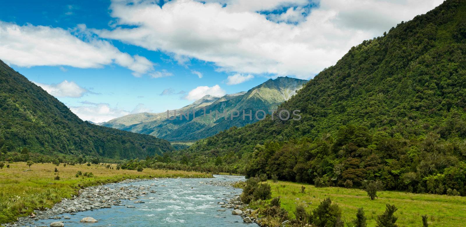 river flowing through a valley with mountain massive in the back ground